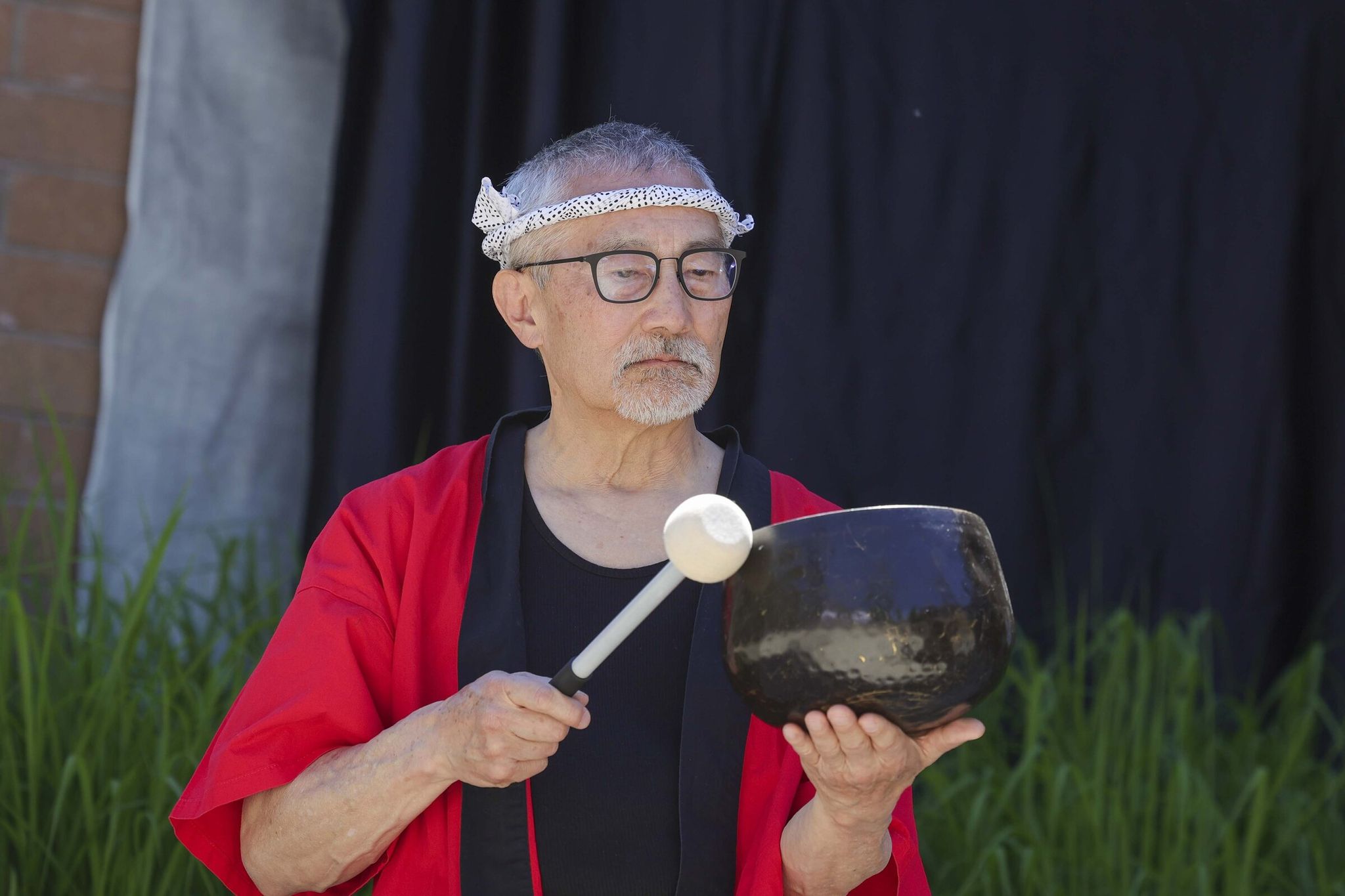 Stan Shikuma together with the Japanese American Citizens League and Tsuru for Solidarity leads a meditation with artist and activist Erin Shigaki during the dedication ceremony marking the permanent installation of her mural 'Never Again Is Now' at Bellevue College in Bellevue on Thursday. (Ivy Ceballo / The Seattle Times)