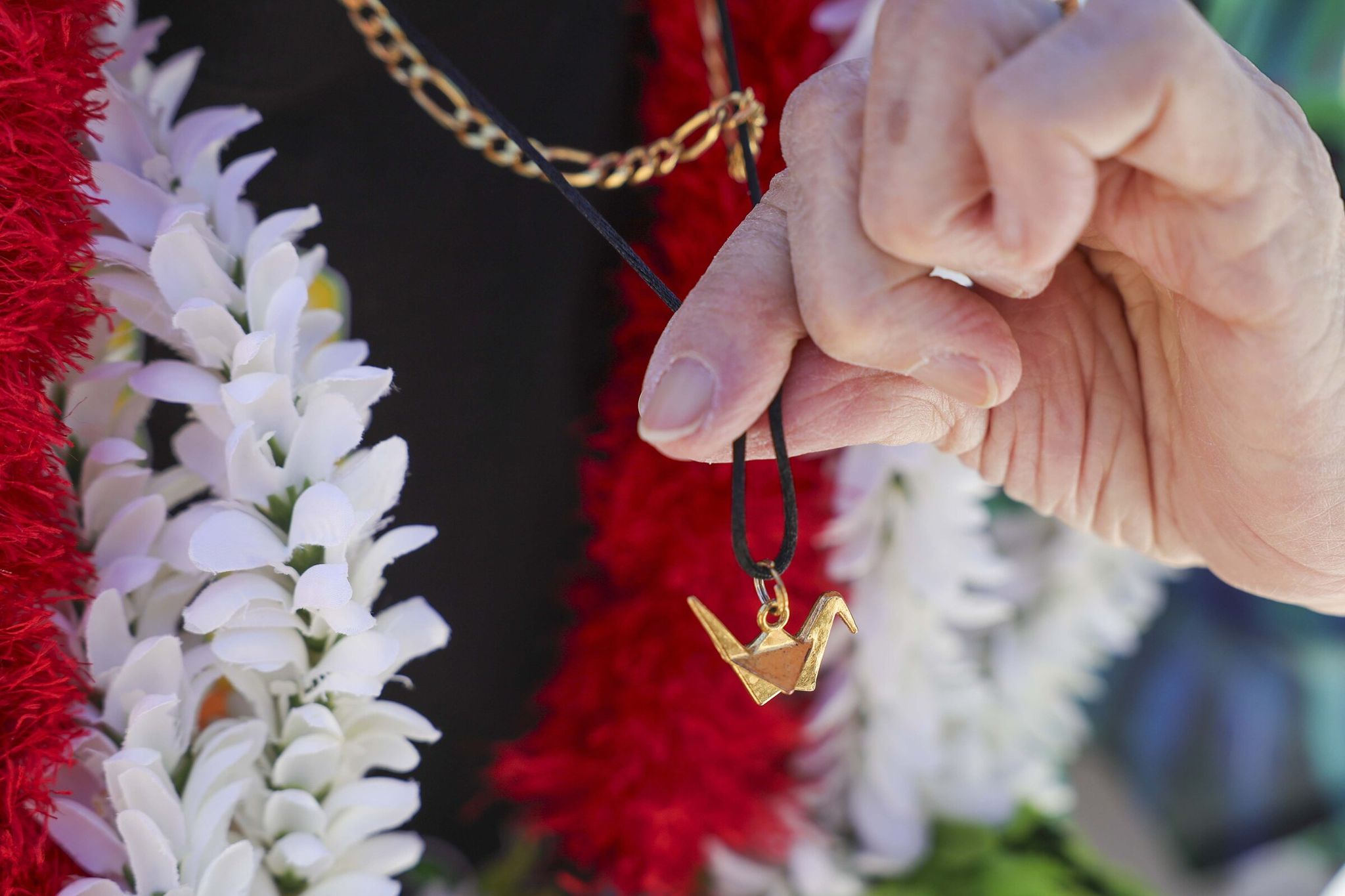 Keiko Yanagihara, 85, a Japanese American who survived incarceration at Minidoka during World War II, displays a crane she wears following the dedication ceremony marking the permanent installation of artist and activist Erin Shigaki’s mural 'Never Again Is Now' at Bellevue College in Bellevue on Thursday. (Ivy Ceballo / The Seattle Times)