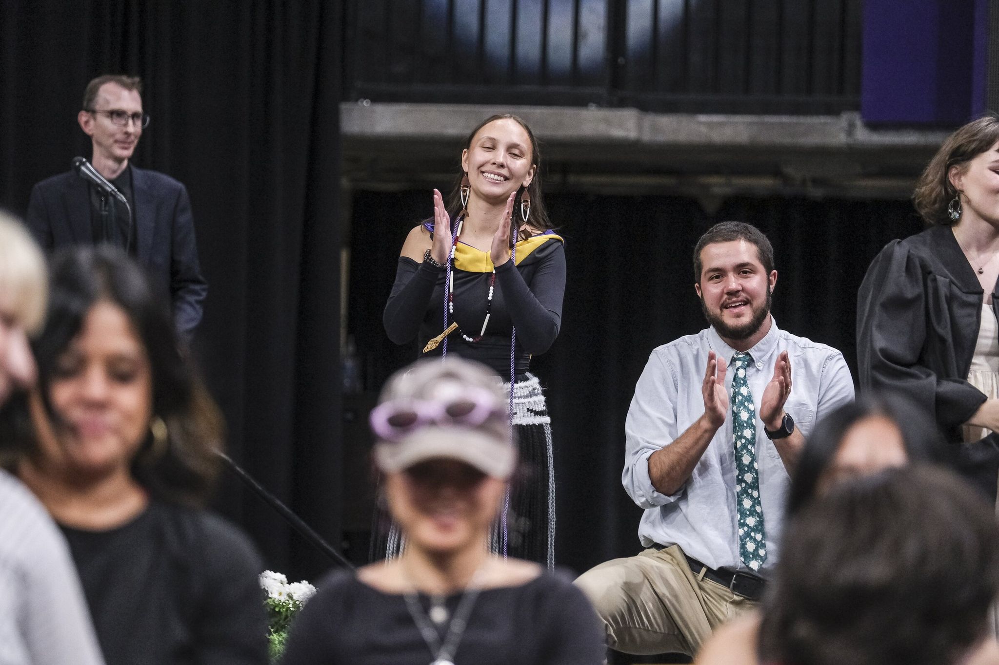 Rosalie Fish, center, applauds while other graduates practice a line dance they will perform during ceremonies for the University of Washington School of Social Work. (Dean Rutz / The Seattle Times)