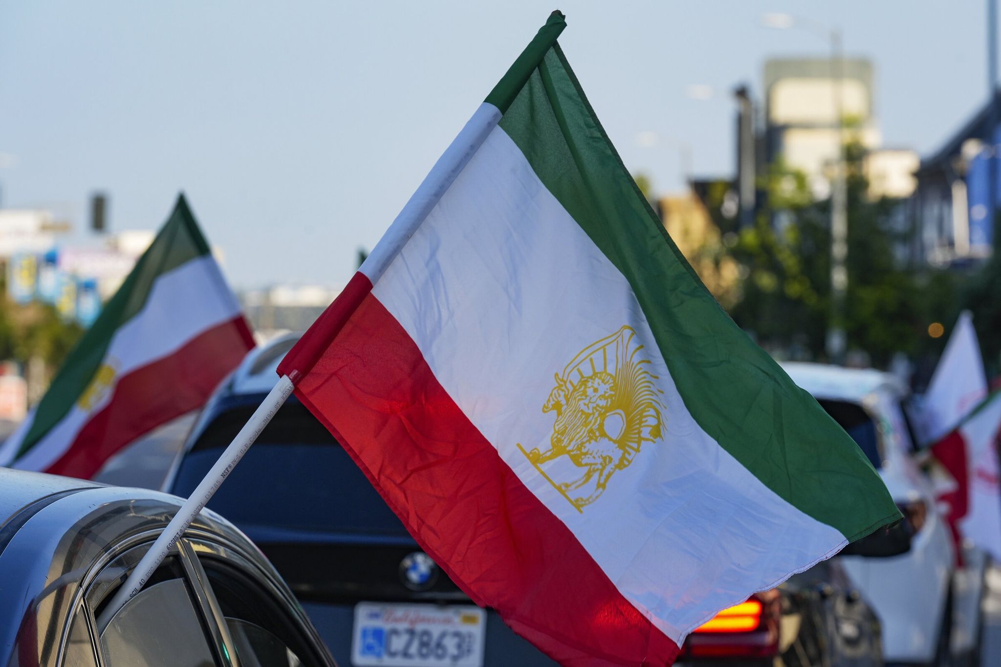 A caravan of vehicles drives while flying the lion-and-sun flag along Westwood Boulevard in the Westwood district of Los Angeles. The flag continues to be used by the Iranian diaspora, monarchists and opposition groups as a symbol of Iran’s pre-Islamic heritage and resistance against the Islamic Republic. (Damian Dovarganes / AP, 2024)