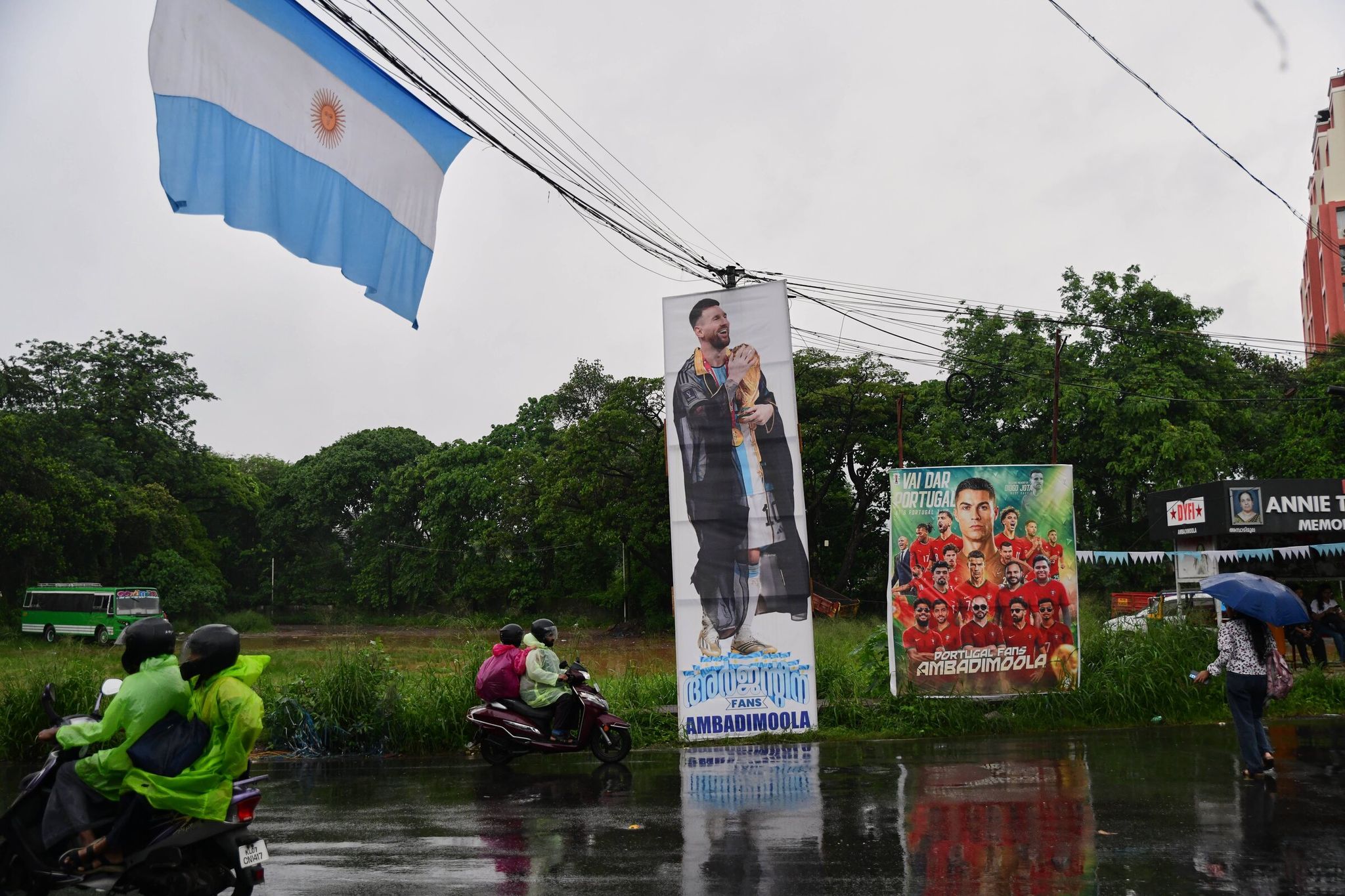 Passengers in India pass posters put up by World Cup fans on Friday during monsoon rains in Kochi, in the coastal state of Kerala. (R. S. Iyer / The Associated Press)