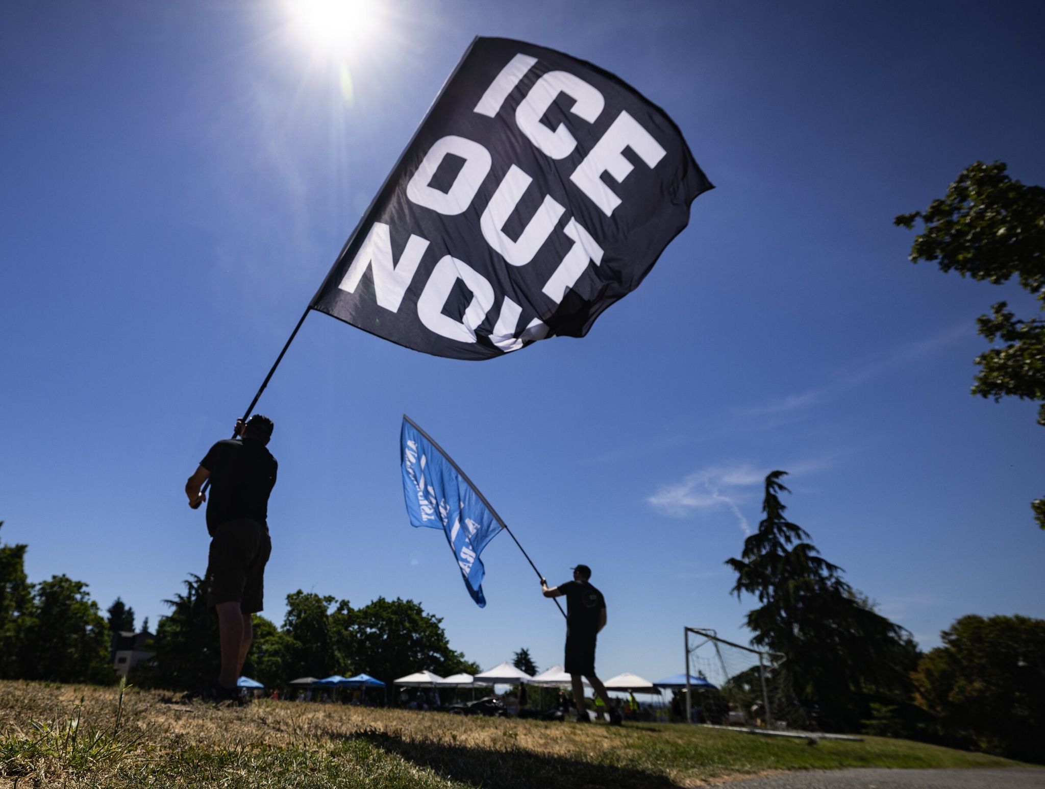 People wave flags at an anti-ICE rally Sunday at Judkins Park in Seattle, on the eve of the first FIFA World Cup game to be hosted in the city. (Ken Lambert / The Seattle Times)