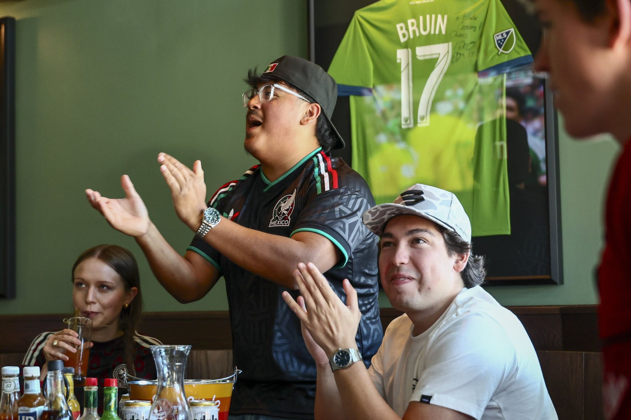 Left to right: Lindsey Olson, Luis Arriaga and Diego Navarro cheer for Mexico as El Tri battles South Africa at the World Cup on June 11. The Atlantic Crossing bar at Green Lake is a magnet for soccer fans while the tournament sweeps North America. (Kevin Clark / The Seattle Times)