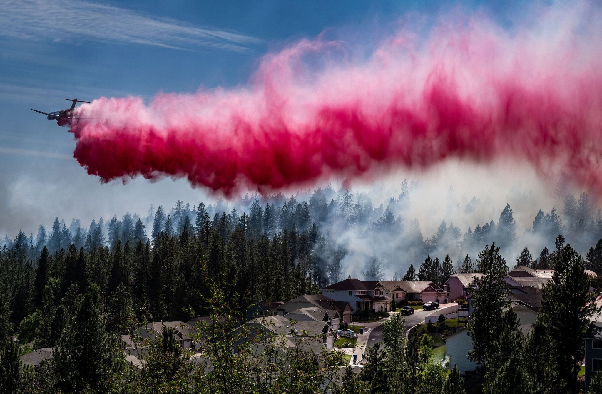 An aircraft tanker drops fire retardant on a neighborhood near Spokane Tuesday. The fire consumed several houses, but firefighters prevented many more from burning. (Colin Mulvany / The Spokesman-Review)