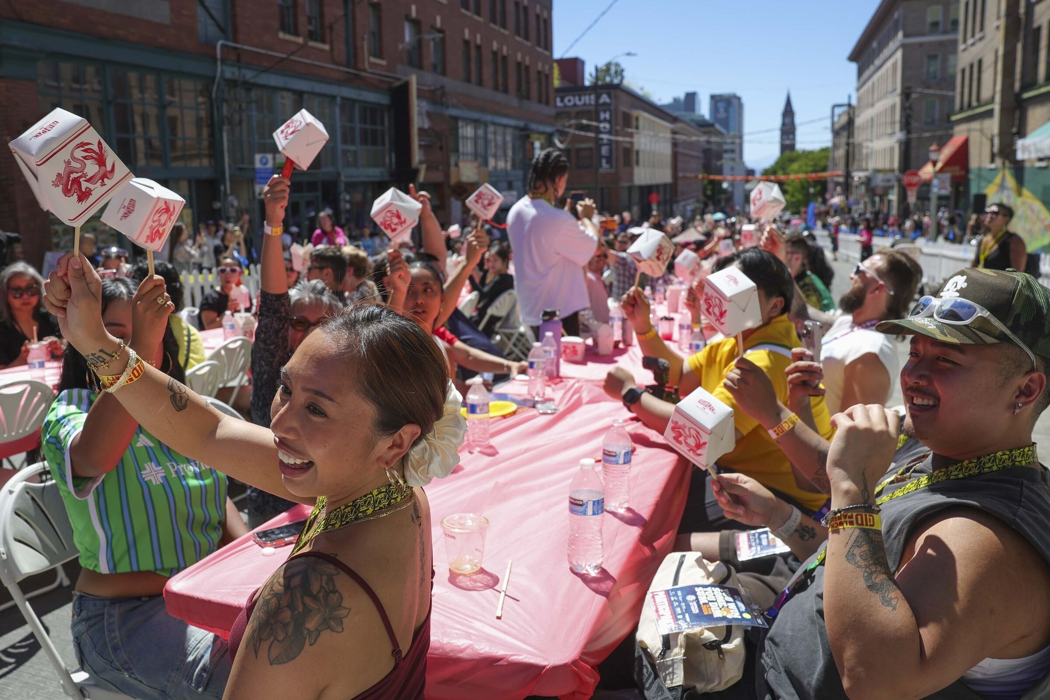 Participants celebrate finishing their portions while attempting to break the Guinness World Record for largest dim sum lunch during the Chinatown International District’s summer kickoff block party Thursday. In the end, 830 participants wolfed down more than 3,000 pork-and-shrimp dumplings and buns during the record attempt. (Ivy Ceballo / The Seattle Times)