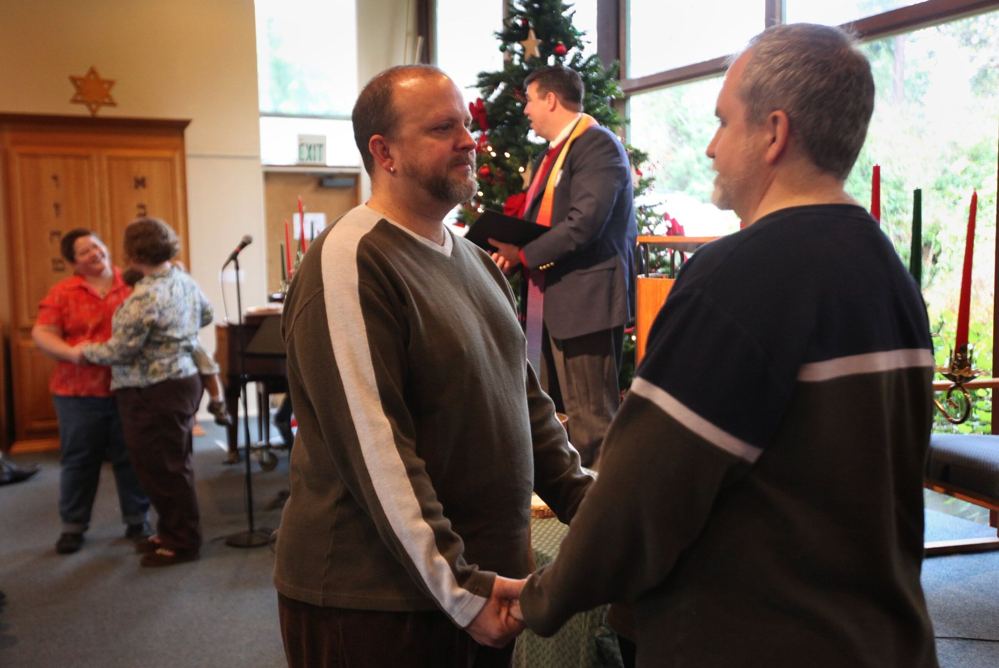 Geoffery and Devin McAnalloy (foreground) and Katrina Gutleben and Melinda Brooks marry at Saltwater Unitarian Universalist Church in Des Moines in December of 2012. The Rev. James Kubal-Komoto presided over the weddings. (Ellen M. Banner / The Seattle Times)