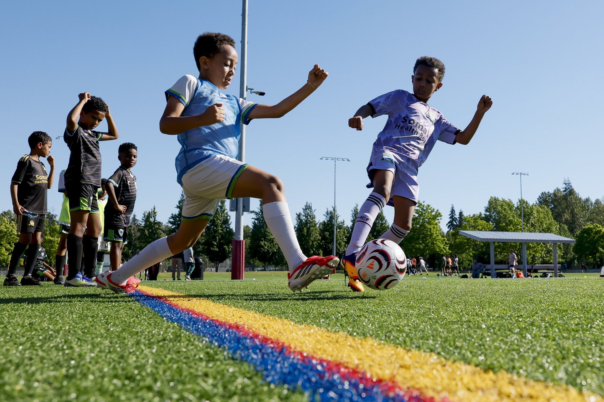 Substitute players wait while participants battle for the ball along the sideline during a 3-on-3 soccer tournament in Seattle (Jennifer Buchanan / The Seattle Times).