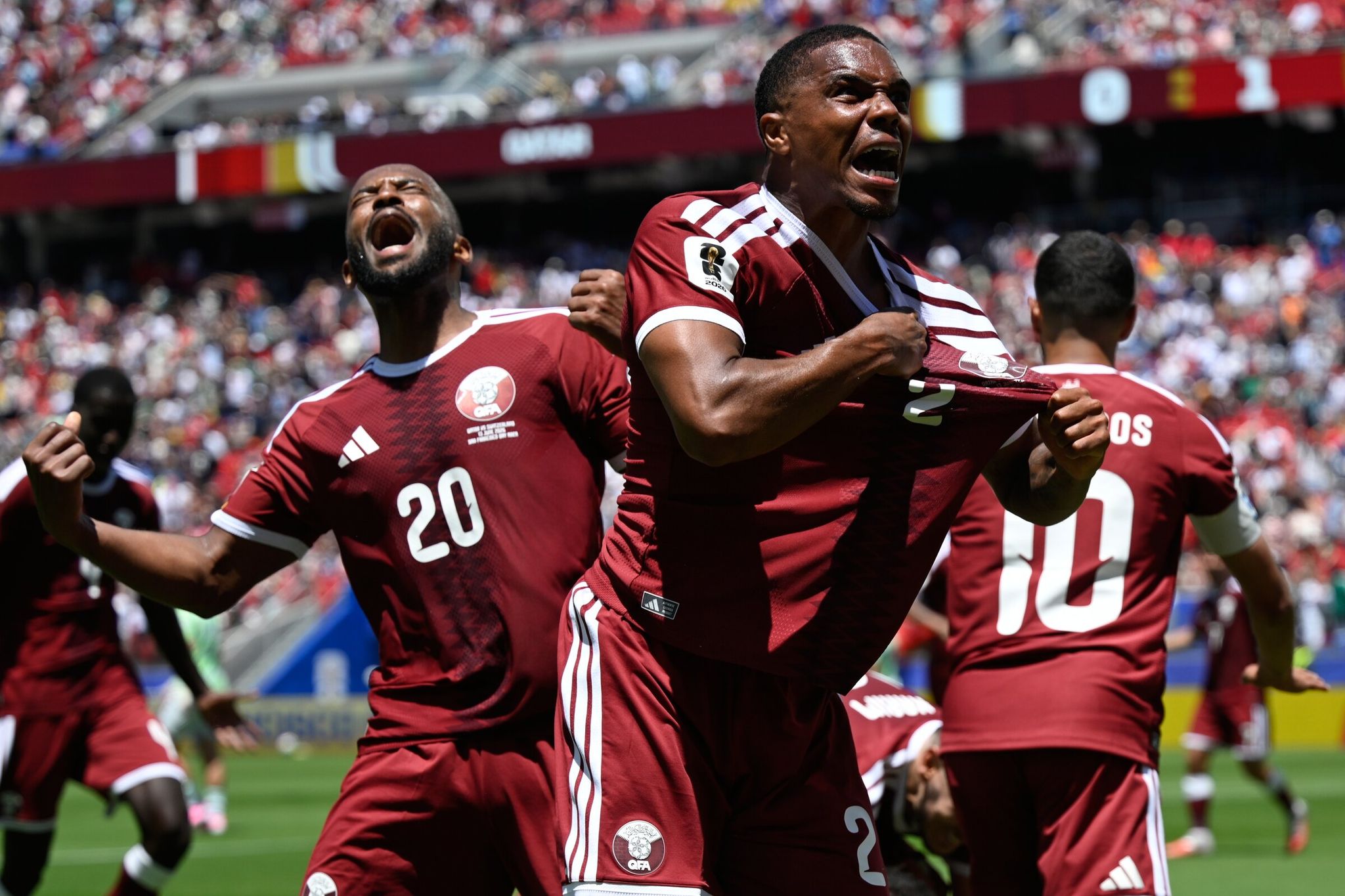 Pedro Miguel of Qatar celebrates with teammate Buaalem Khukhi after the latter scored his team’s first goal in the World Cup match against Switzerland on June 13. (Ekin Howard / AP)