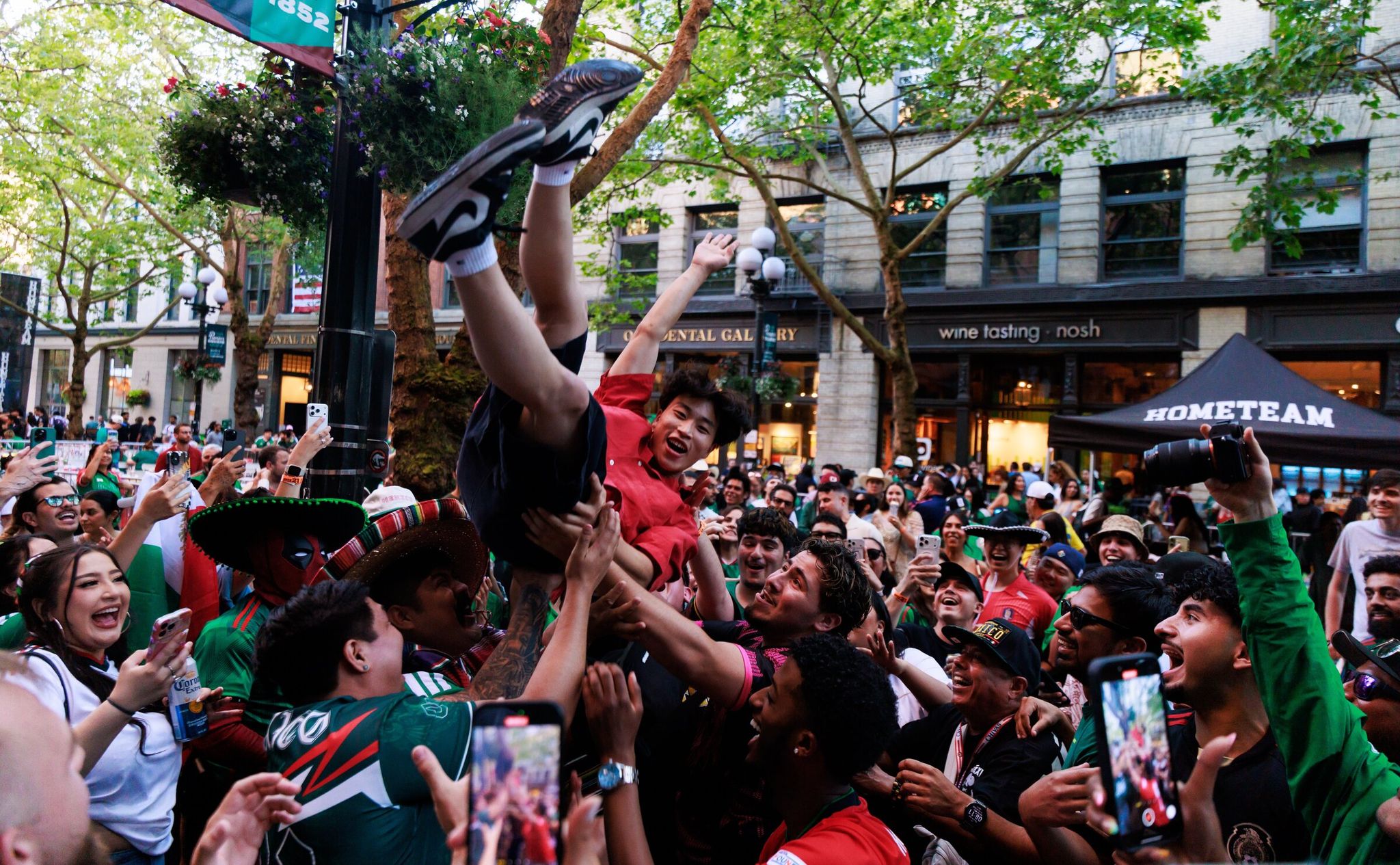 Fans — including Tyson Dong in red — celebrate during a World Cup viewing party for Mexico vs. South Korea at Pioneer Square on June 18. Mexico won 1-0. (Erika Schultz / The Seattle Times)
