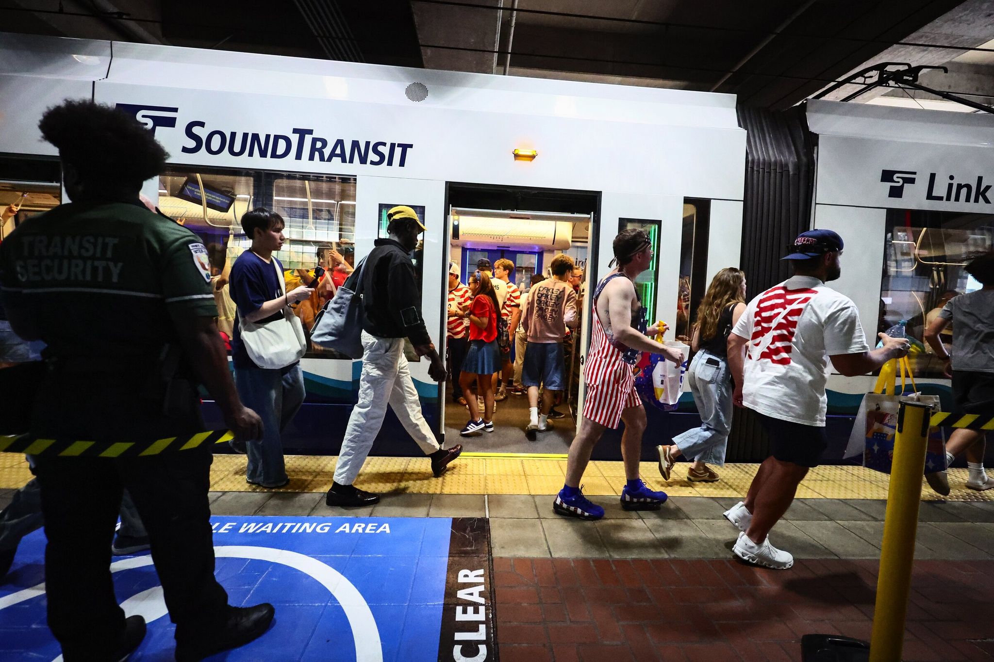 Soccer fans board trains as the transportation security service manages crowds at the Chinatown International District light-rail station after the June 19 U.S. vs. Australia match. (Kevin Clark / The Seattle Times)