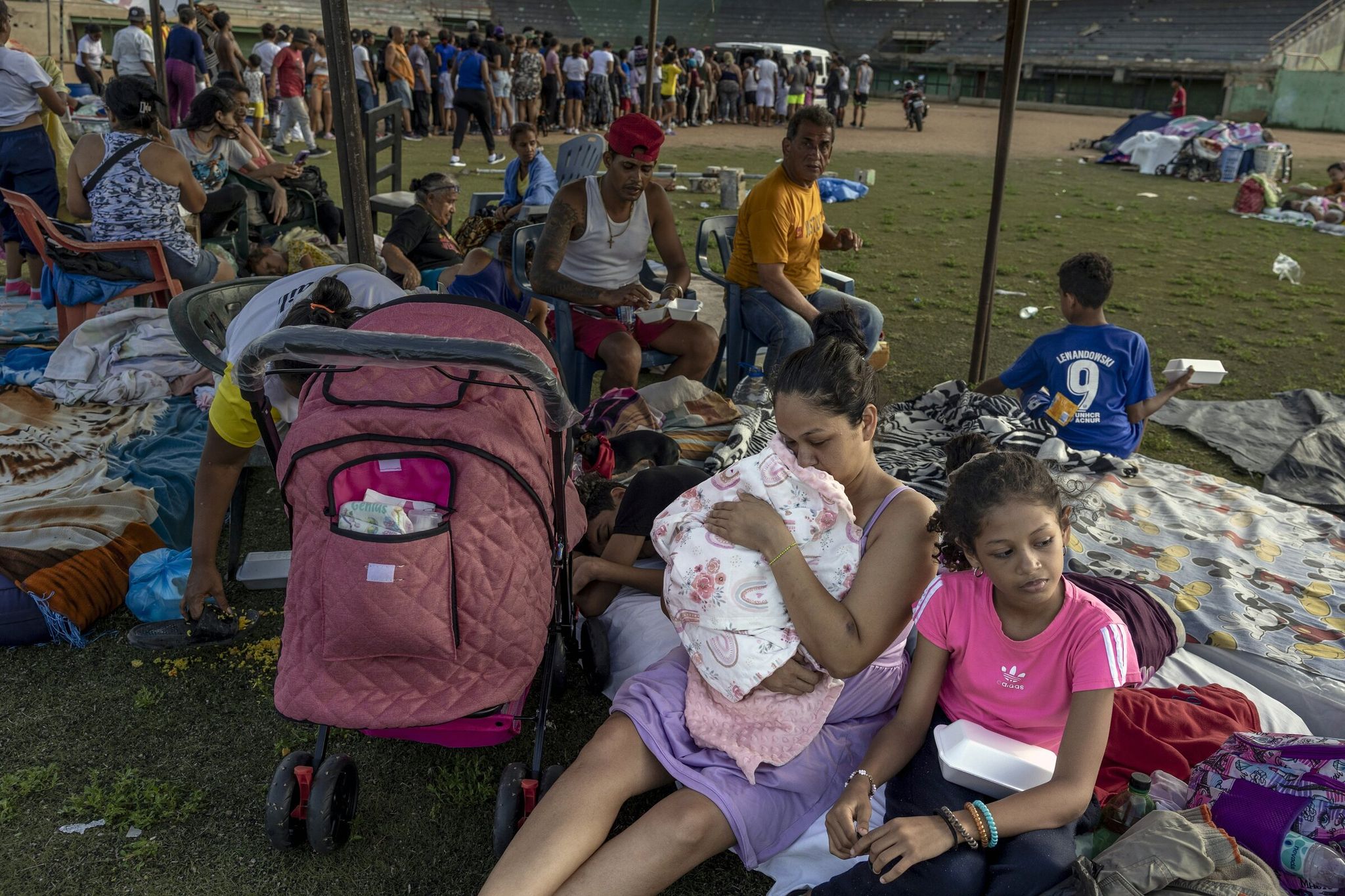 Gusmaira Rizo holds her newborn on Thursday as she and her family, who were forced to leave their home due to the earthquakes, settle into a local baseball stadium in La Guaira. Rizo gave birth two days before the tremors and left her newborn at the hospital; after she managed to get out from under the rubble of her home, she made it back to the hospital and was reunited with her child. (Fabiola Ferrero / The New York Times)