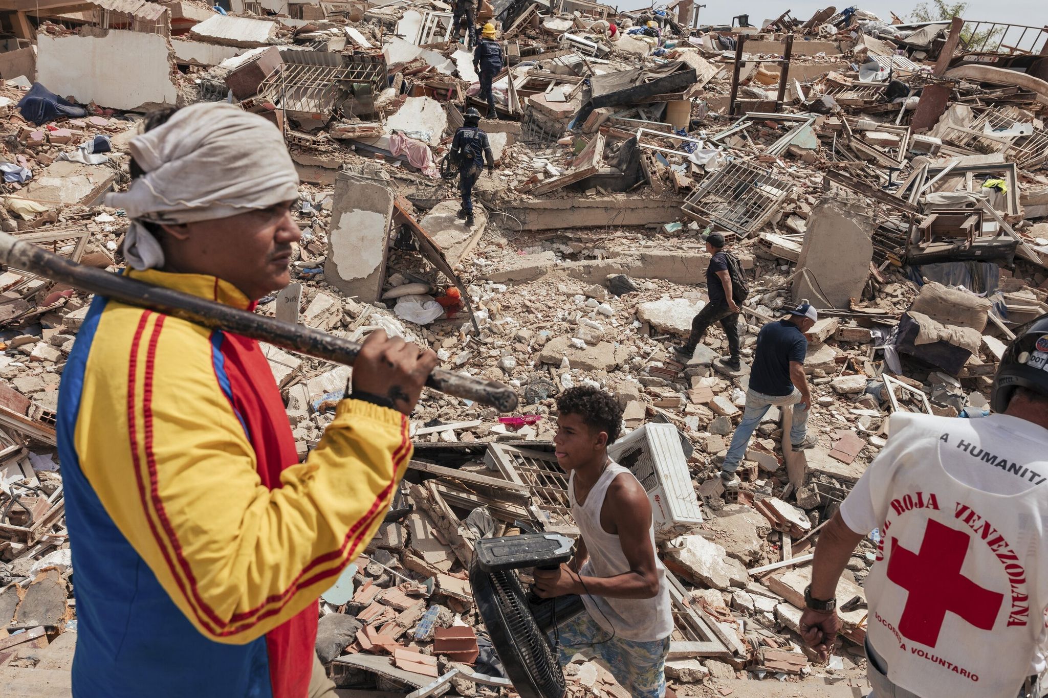 Civilians and first responders walk Thursday through  the rubble of a residential building that collapsed during an earthquake Wednesday in Catia La Mar, Venezuela. Rescue crews intensified their search for survivors as Venezuelans began to grapple with the scale of the devastation caused by the worst earthquakes to hit the country in nearly six decades. (Adriana Loureiro Fernandez / The New York Times)
