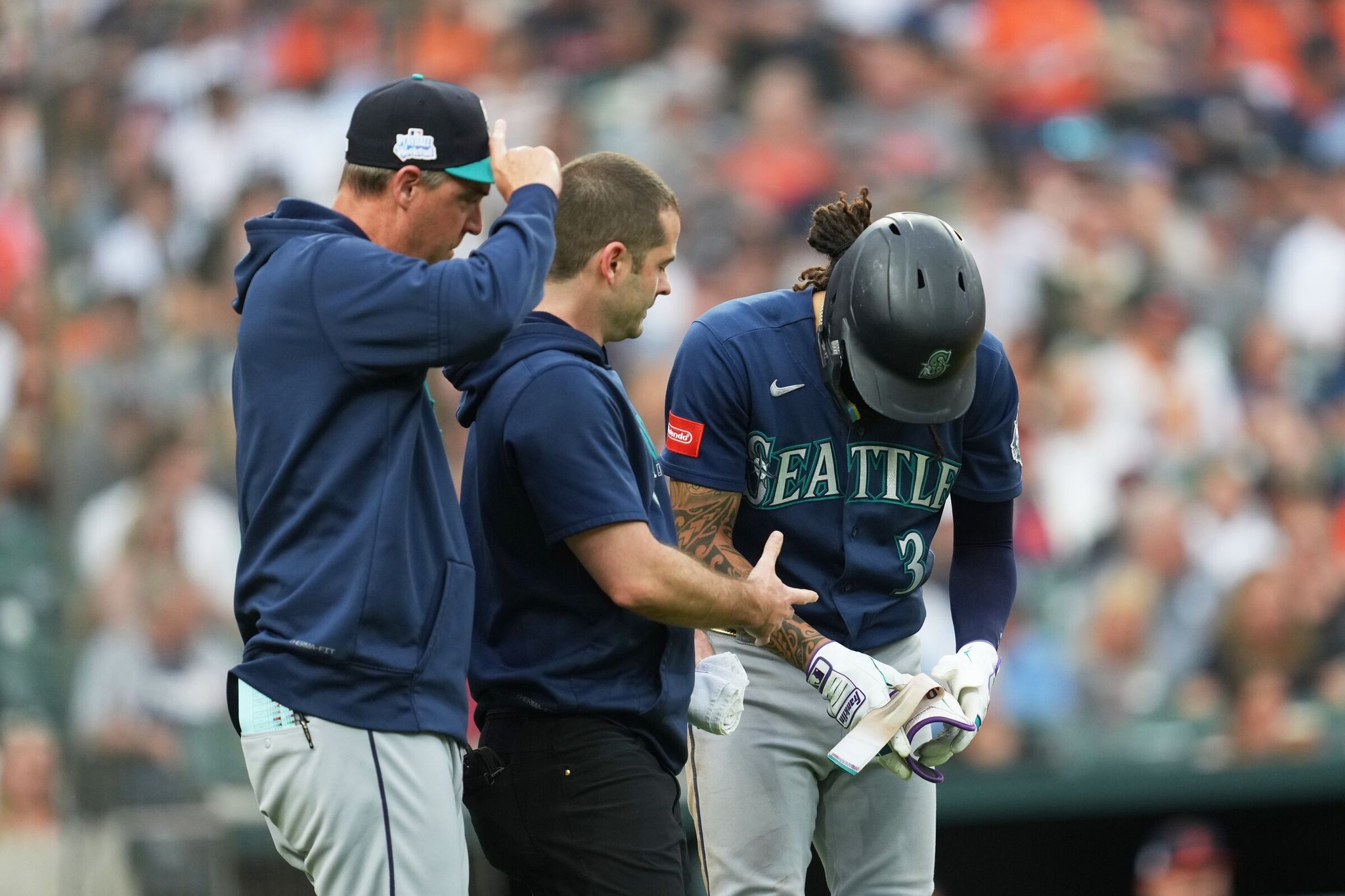 Seattle Mariners player J.P. Crawford (right) is examined by trainer Kevin Orlosky (center) and manager Dan Wilson (left) after being hit by a pitch in the third inning of a baseball game against the Detroit Tigers on Friday, June 5, 2026, in Detroit. (AP Photo/Paul Sancya)