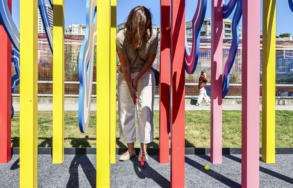 Jen Bucksh positions herself for a tough shot on the summertime mini-golf course at Olympic Sculpture Park in Seattle. (Kevin Clark / The Seattle Times)