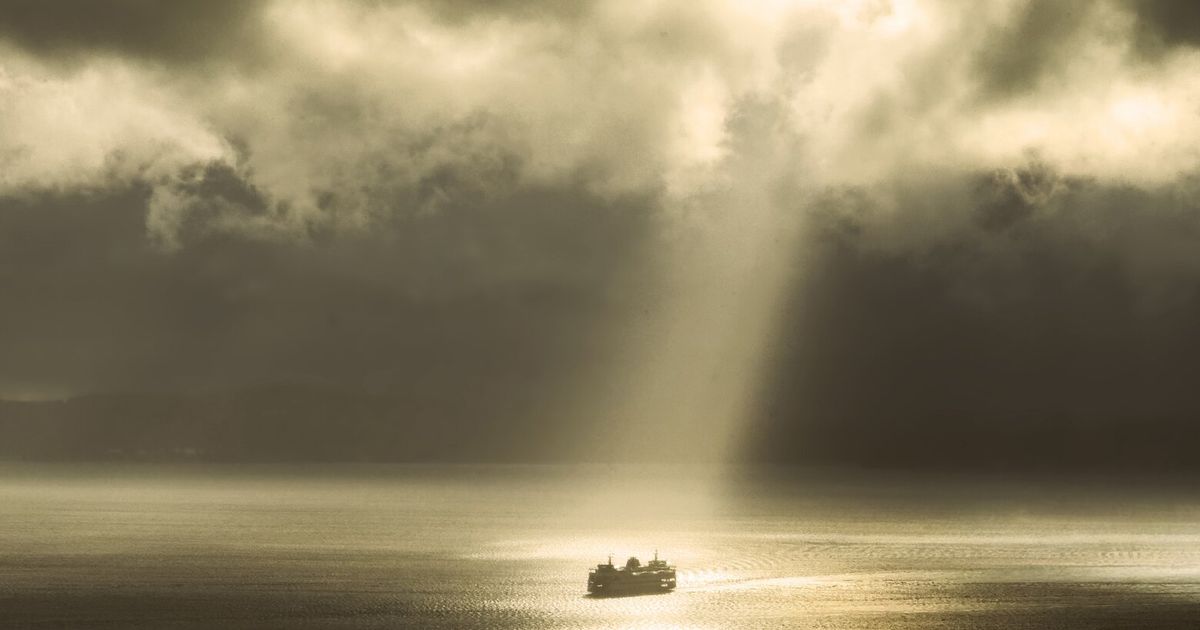 A ray of sun breaks through the clouds, spotlighting a Puget Sound ferry