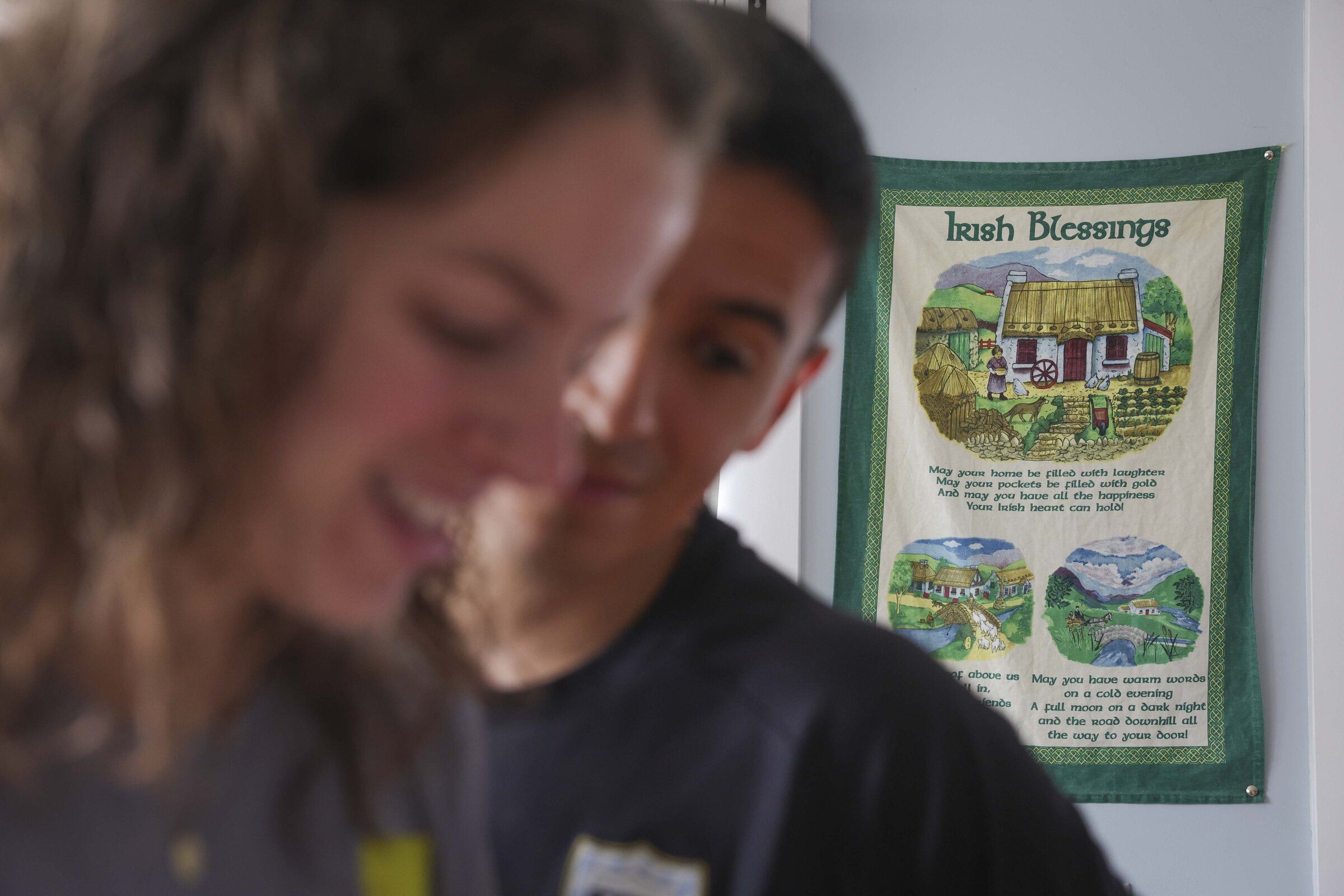 An Irish blessing hangs near the entrance as Matty Gottbrath (left) and Jorge Aranda (right) look at photos from a race they ran together before going for a run at their home in Seattle on Saturday, June 27, 2026. (Ivy Seballo / The Seattle Times)