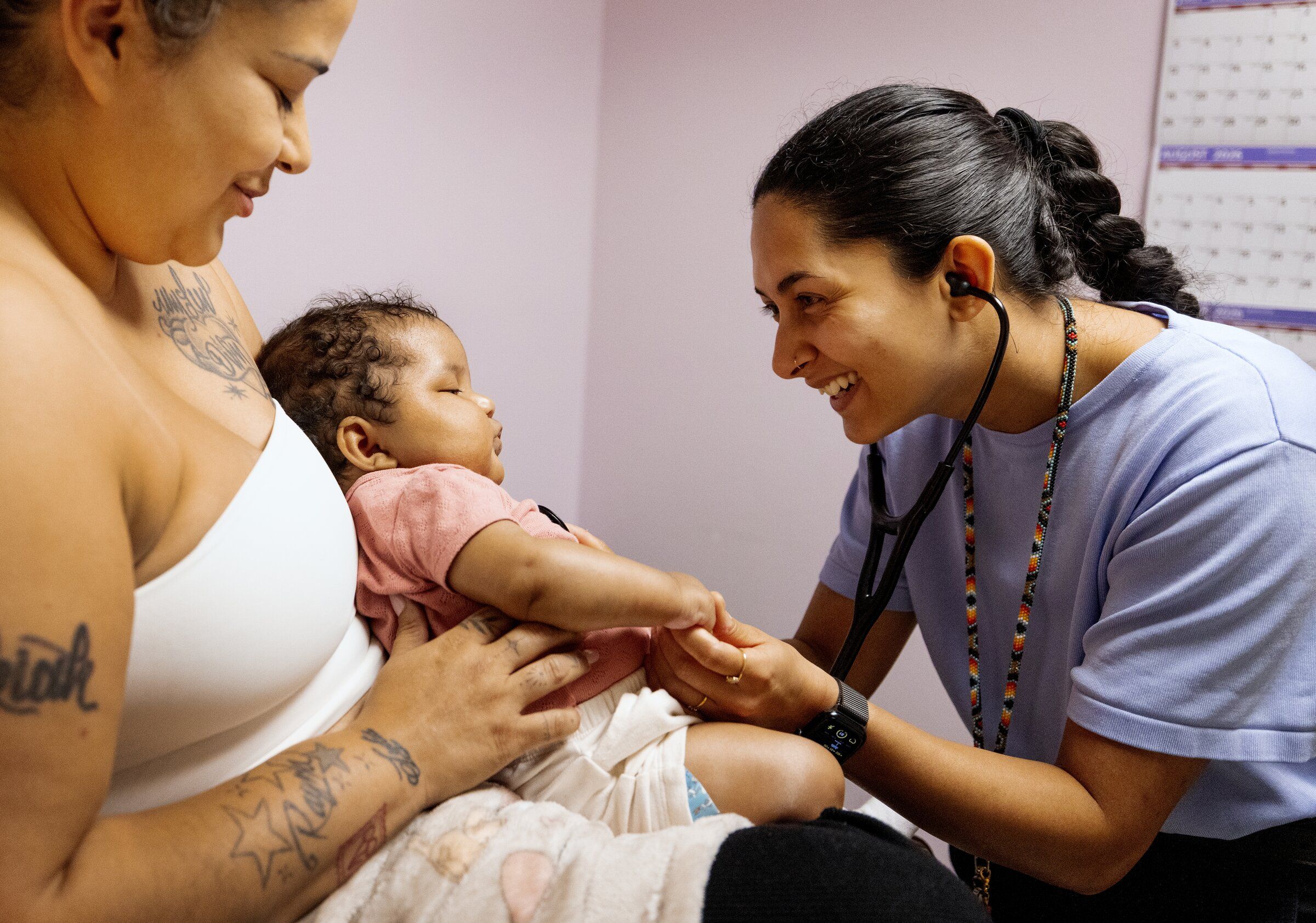 Dr. Ashvini Vaidya, right, a Providence Swedish resident at Seattle Indian Health Board, checks in with 5-month-old Naziyah and her mom, Rayna Bercier. Bercier said she wanted to cry after she heard the family medicine residency program would cut partnerships with some community clinics. (Ken Lambert / The Seattle Times)