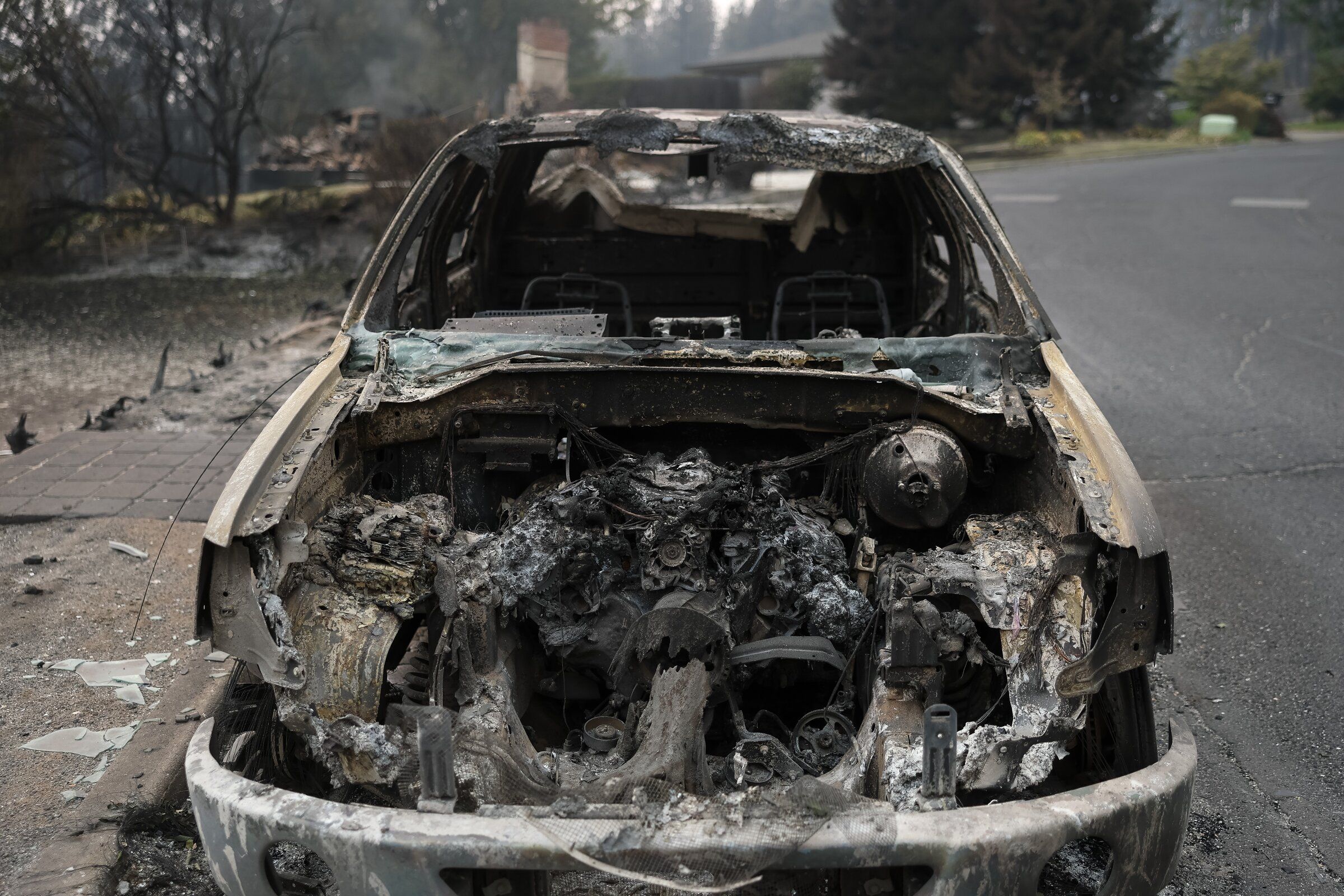 A burned vehicle sits on a street after the Old Trails fire passed through on Sunday in Spokane. (Nick Wagner / The Seattle Times)