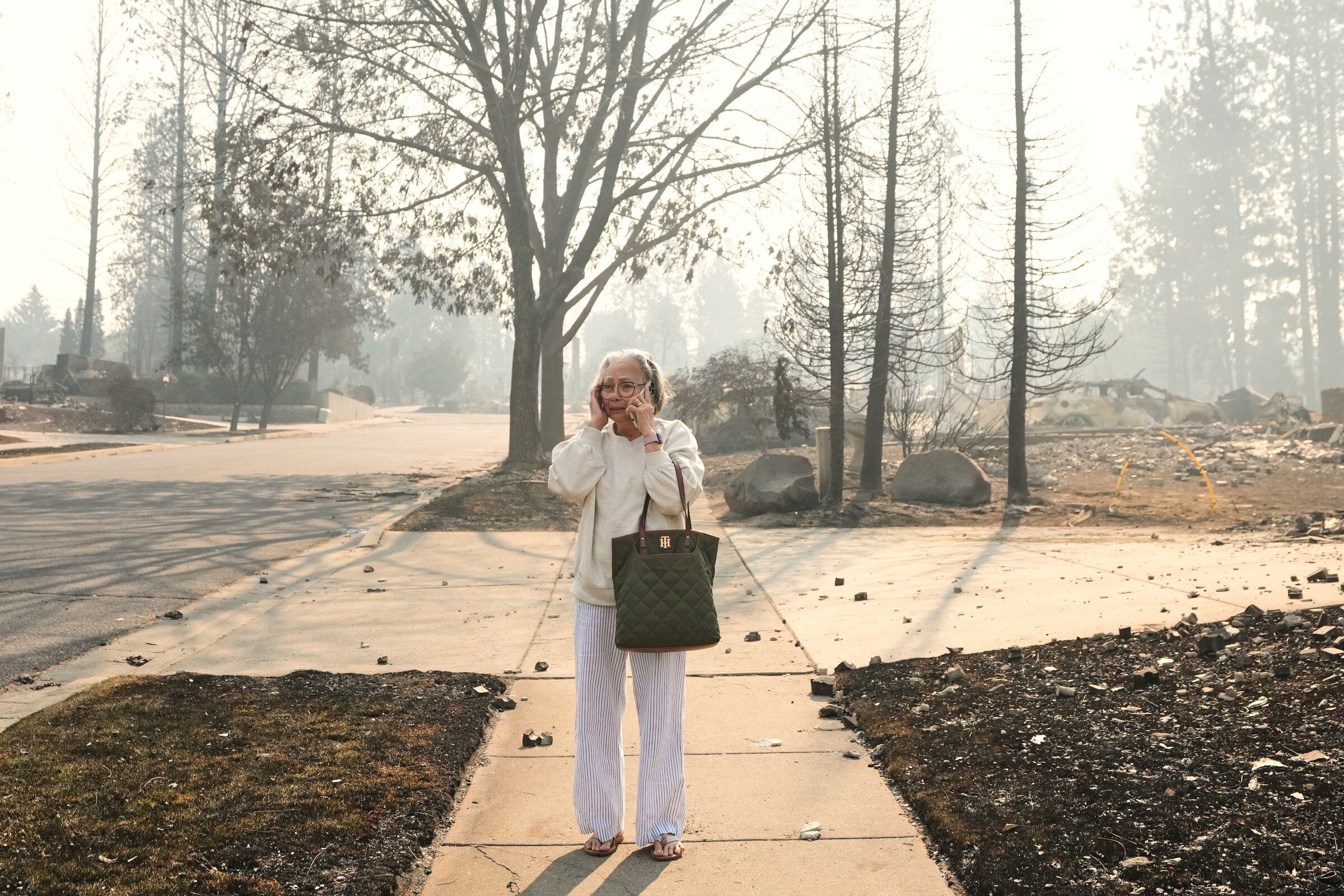 Miriam Sim, 76, reacts as she walks through the burned remains of her neighborhood Monday after a wildfire hit the northern part of Spokane. (Lindsey Wasson / The Associated Press)
