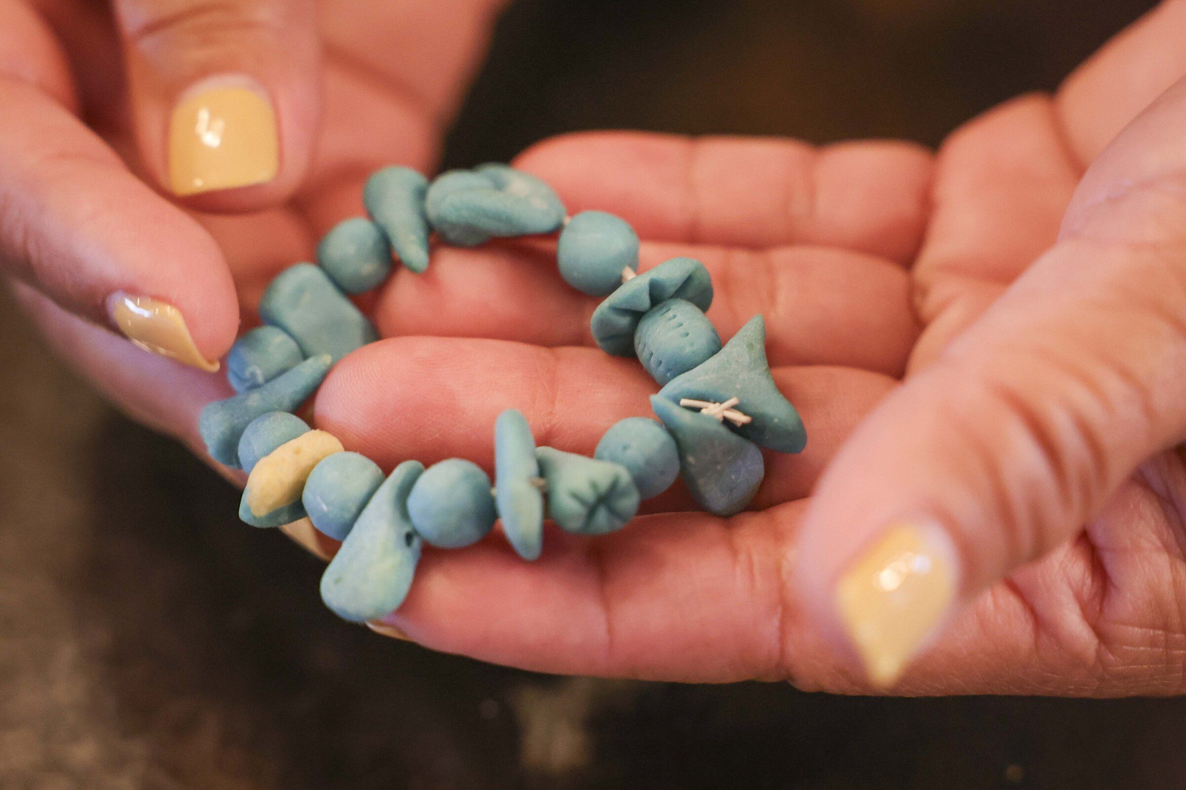 Lewelyn Dixon holds a bracelet made by another woman while they were held at the ICE center in Tacoma. The handmade jewelry was made from belt elastic, and the beads were made from dried rice paste and colored pencils. Dixon still wonders what happened to that woman. (Ivy Seballo / The Seattle Times)