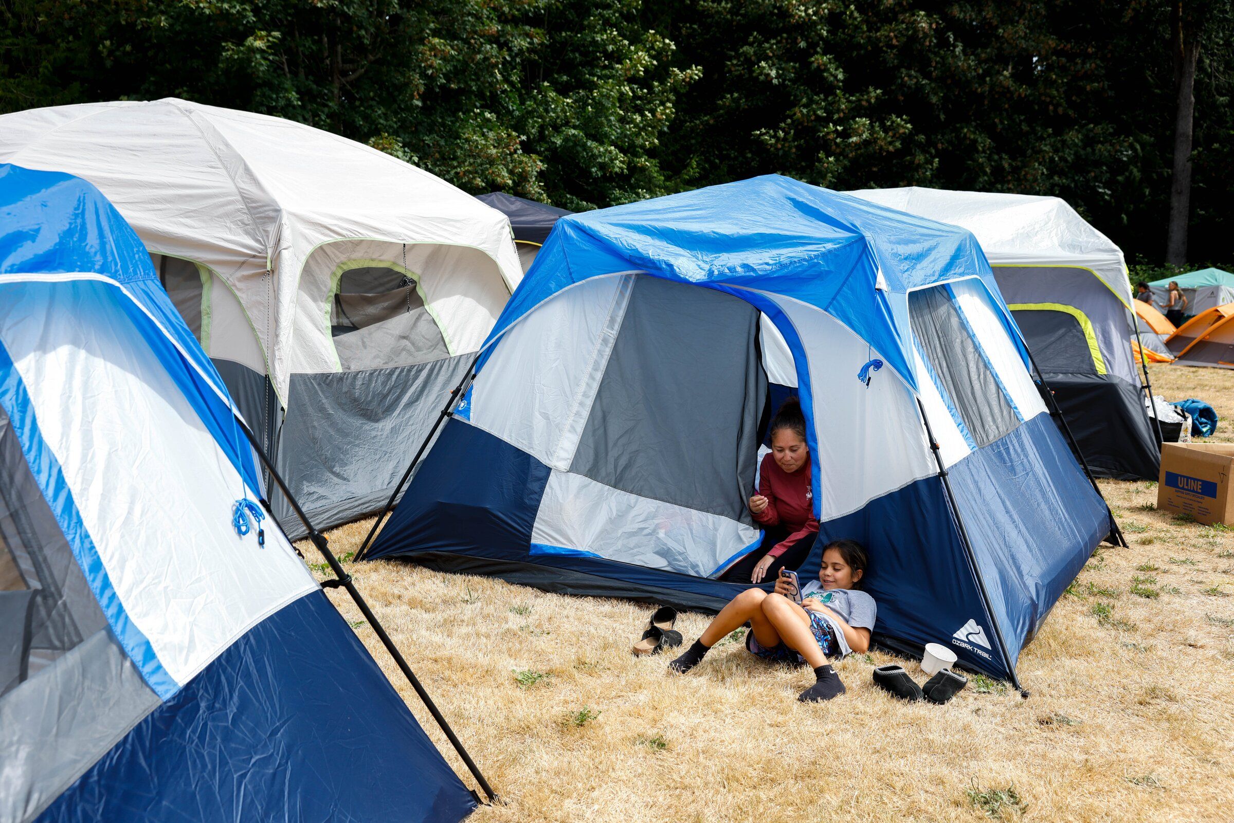 Missy Penn (inside the tent) and Kinsley Penn, both members of the Muckleshoot Tribe, spend time at the Muckleshoot Canoe Family camp in Suquamish during the 2026 Canoe Journey on Tuesday, July 28. (Andrew Burk-Stephenson / The Seattle Times)