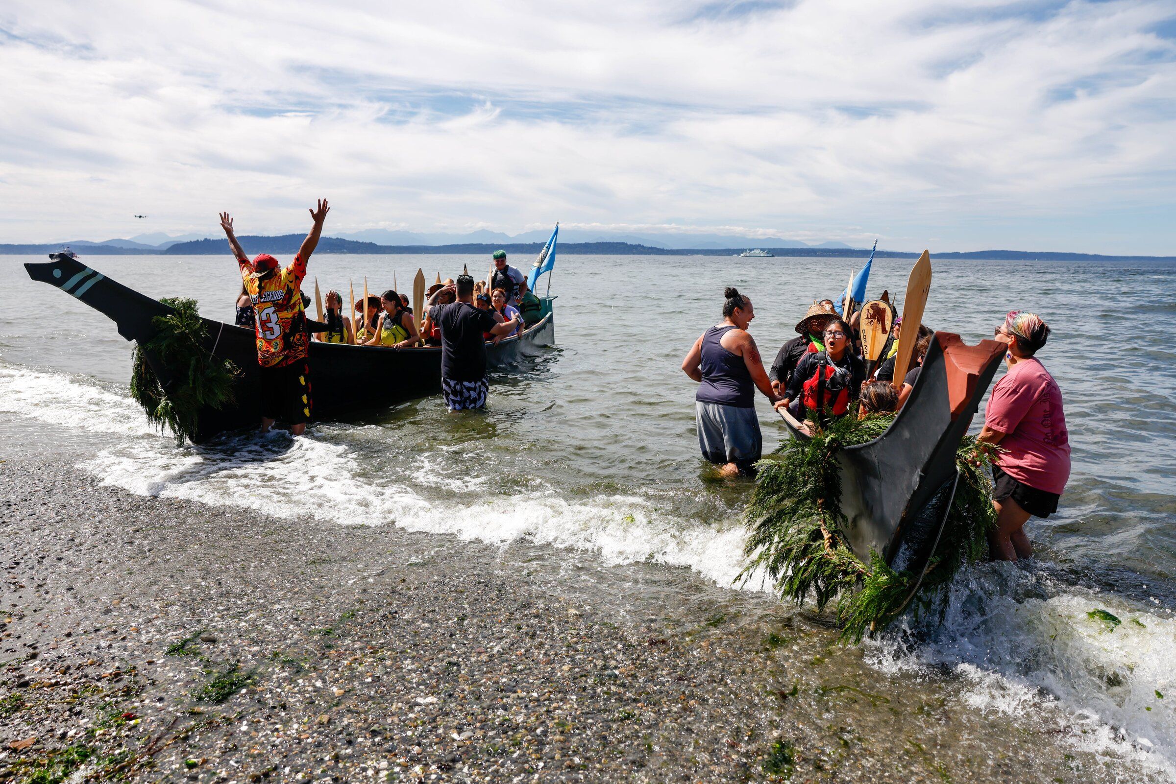 Alongside the Muckleshoot canoe family, the canoe tubšadad səli (Warrior Spirit), pulled by young canoe family members, and yəx̌ʷuləʔ səli (Eagle Spirit) arrive at Alki Beach and ask permission from their Muckleshoot hosts to come ashore in Seattle on Wednesday, July 29. (Andrew Burk-Stephenson / The Seattle Times)