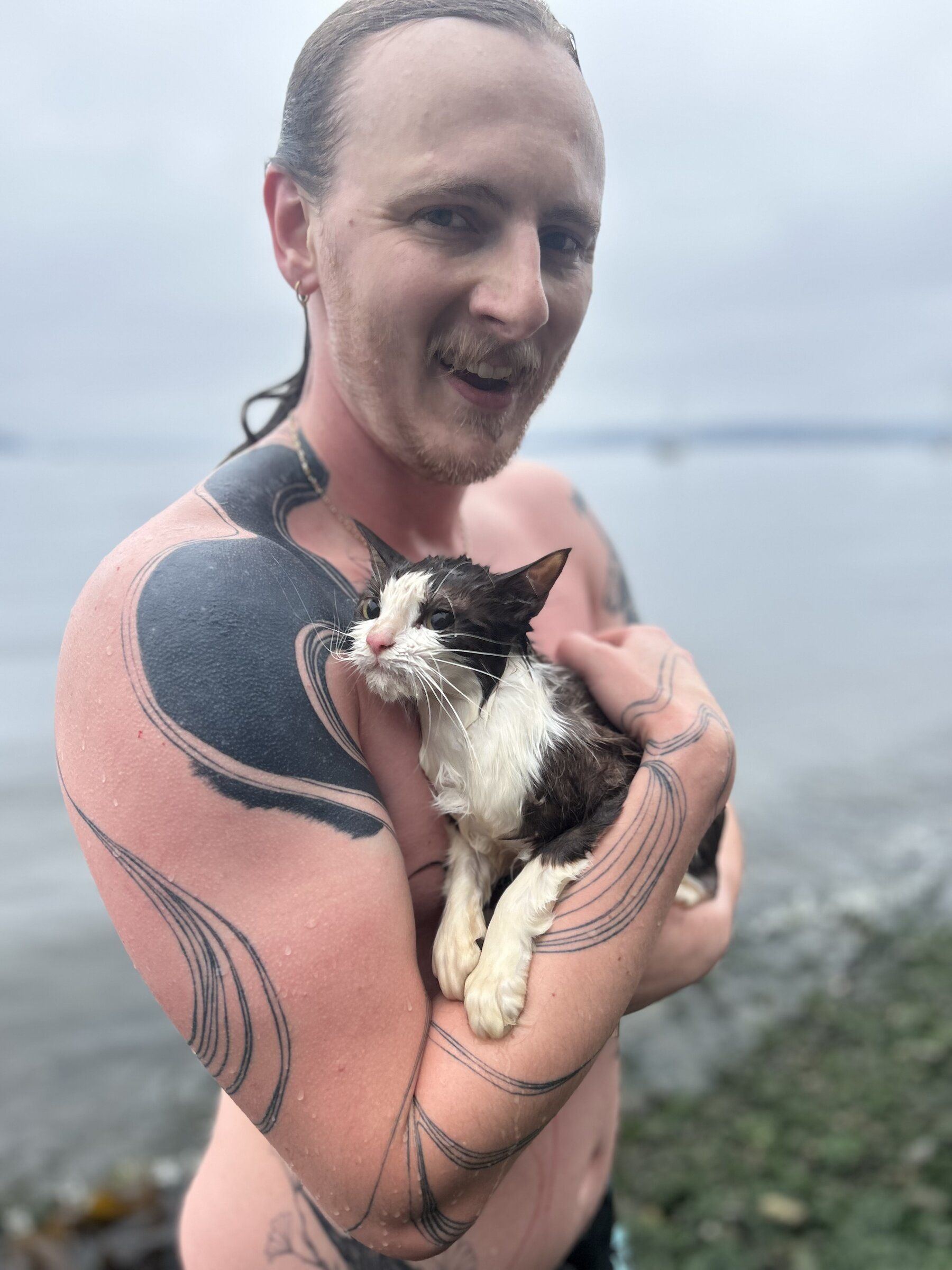 Jesse McConaha, a 26-year-old from Tacoma, holds a dripping wet cat he and a friend rescued from the water near an abandoned sailboat at Tacoma’s Owen Beach on Sunday morning. (Courtesy of Jesse McConaha)