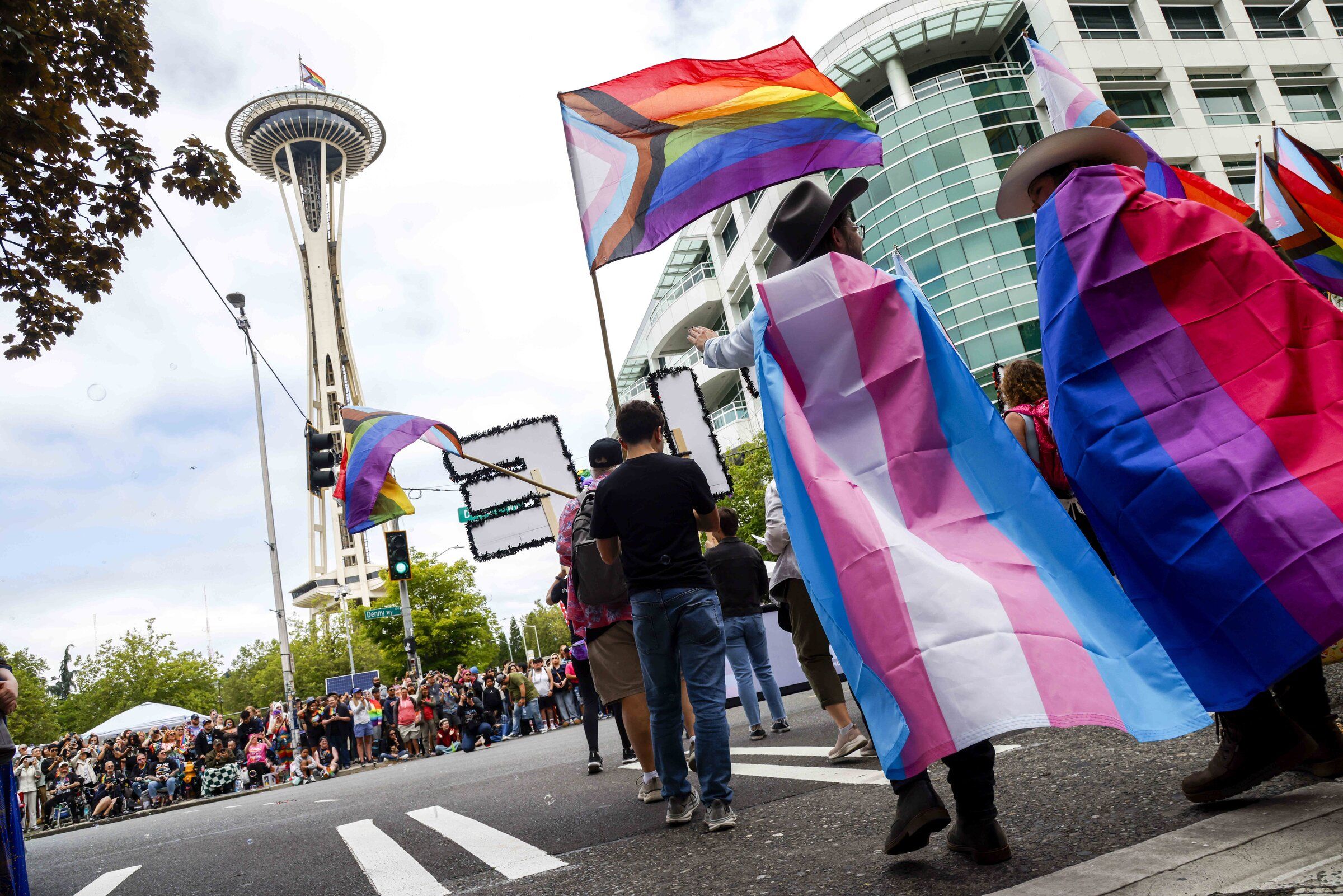People wrapped in flags make their way to Seattle Center during the annual Pride Parade on June 28. (Andrew Burke-Stevenson / The Seattle Times)