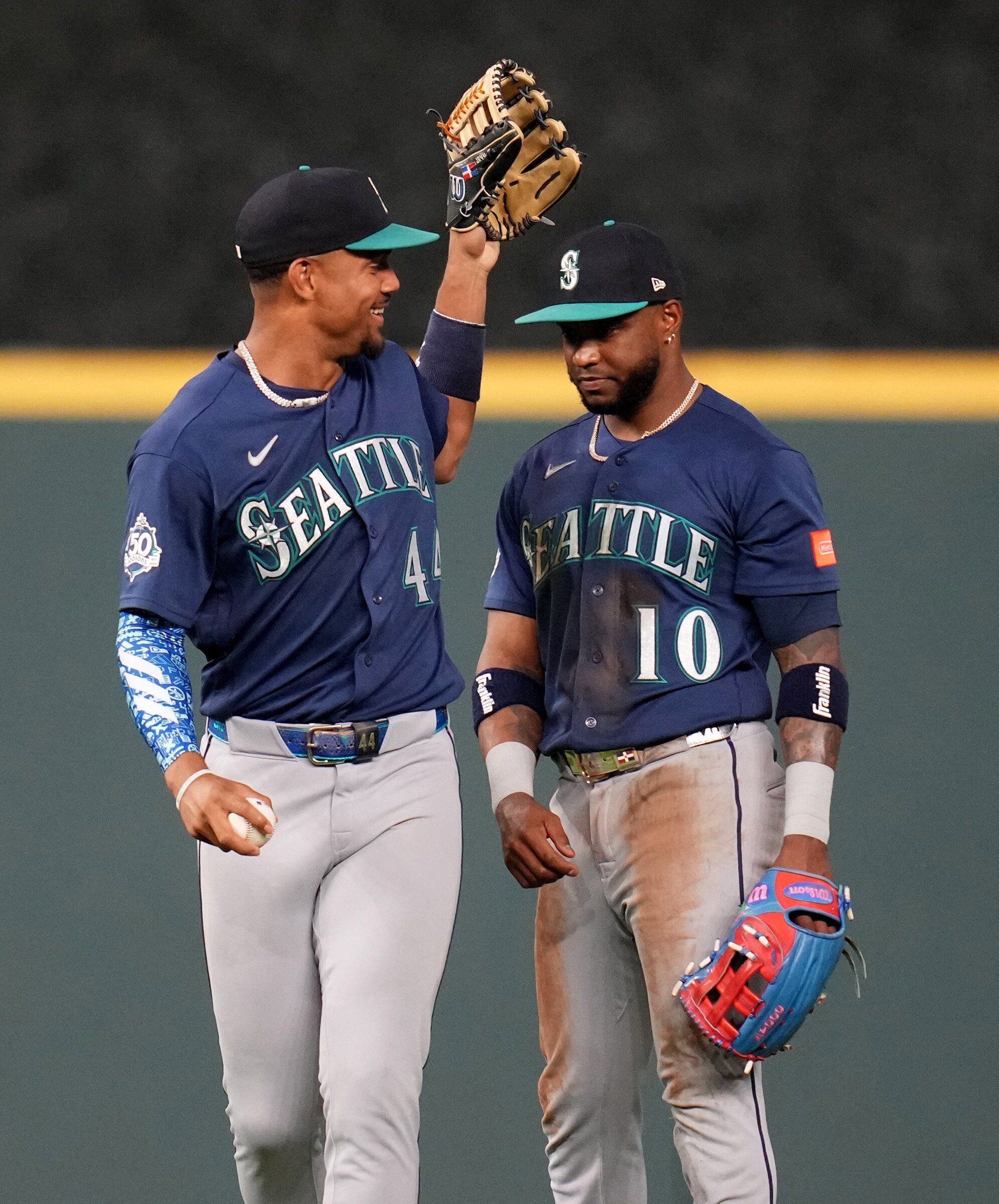 Seattle Mariners center fielder Julio Rodríguez (left) jokes with right fielder Victor Robles (right) after catching a ball hit by Houston Astros' Taylor Trammell in the ninth inning Saturday in Houston. (Karen Warren / Associated Press)