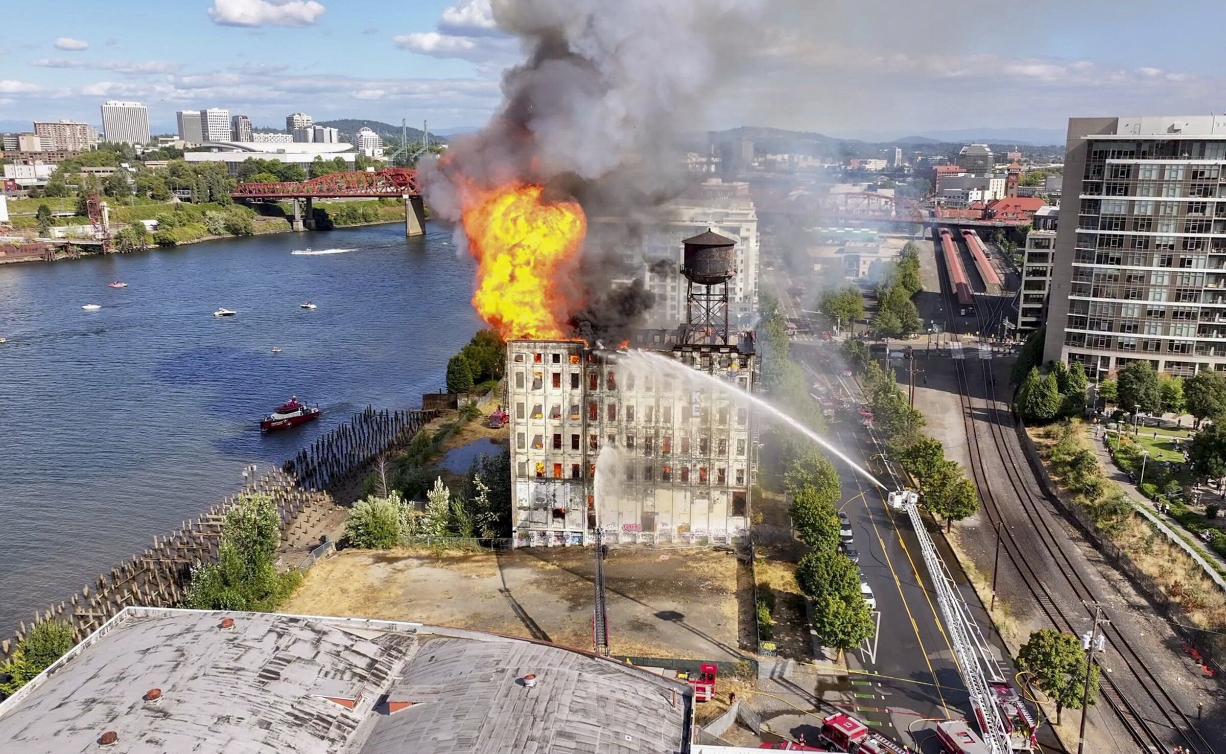 Firefighters battle a blaze at the former Centennial Mills warehouse in Portland this month. Amtrak’s tracks can be seen on the right across the street. (Portland Fire and Rescue via The New York Times)
