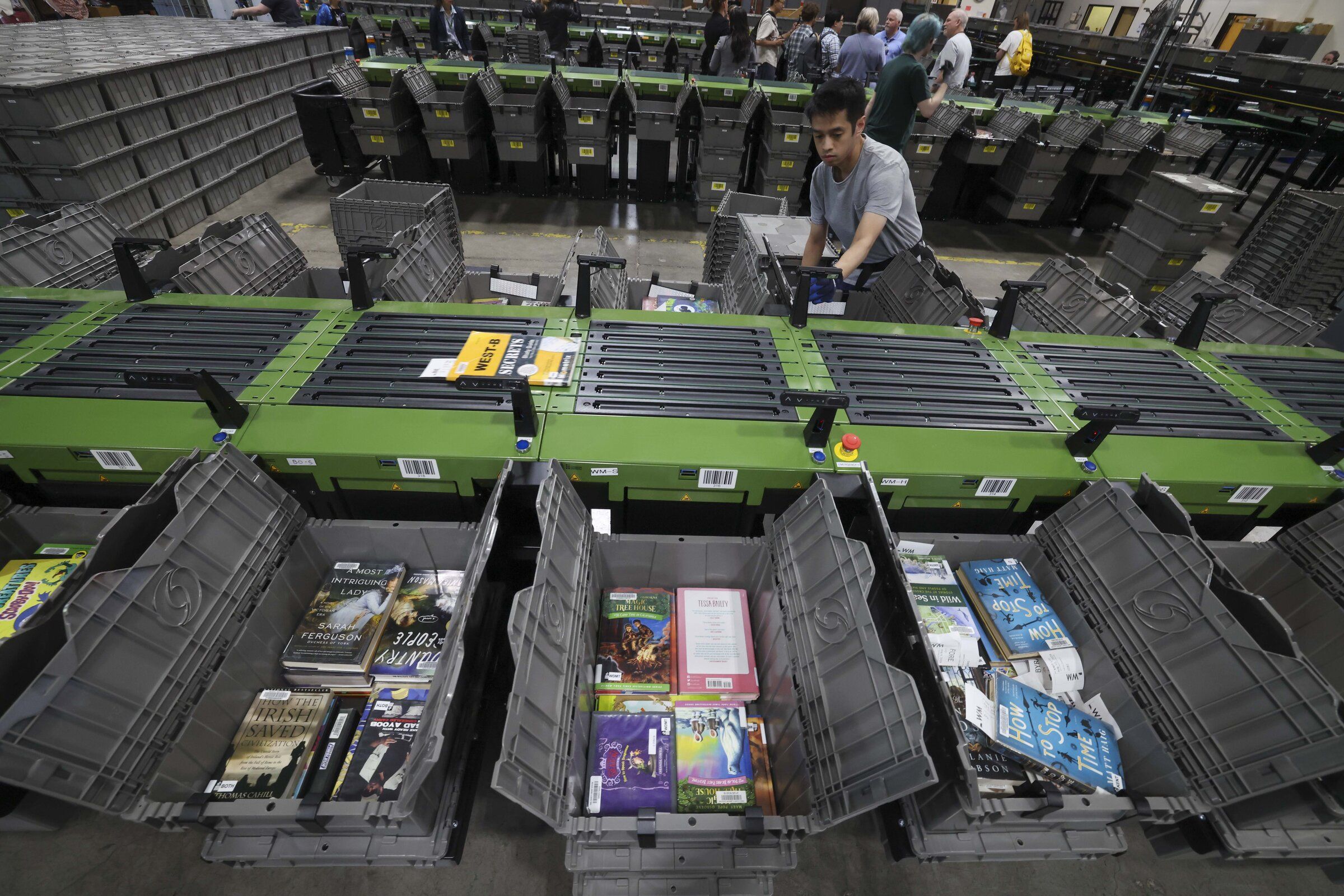 Irwin Ly works with the King County Library System’s new central sorter machine in Renton to get the right materials to the right library. Each day, the sorter handles 25,000 books and other media. (Ivy Ceballo / The Seattle Times)
