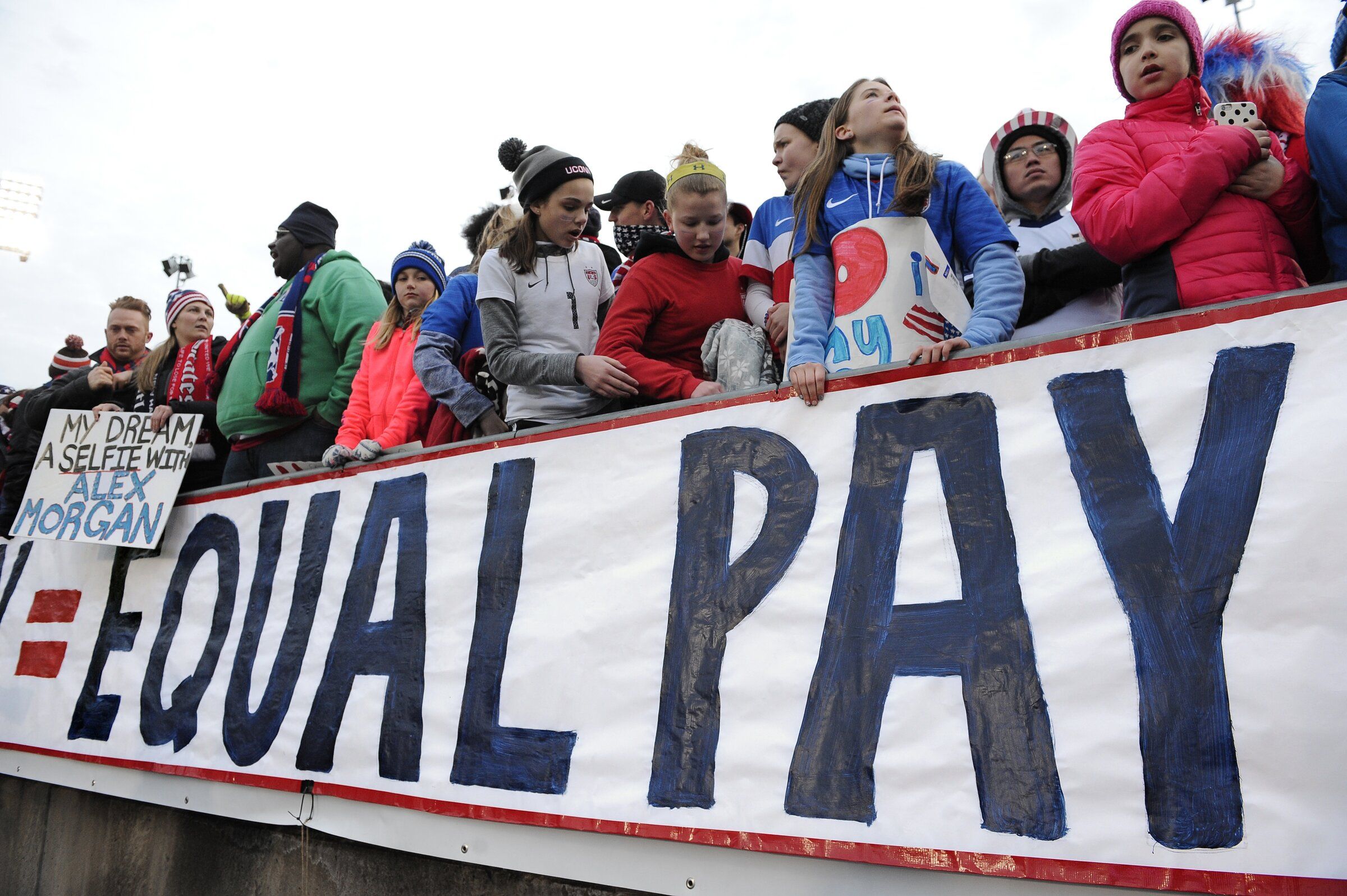 Fans stand behind a large sign to advocate for equal pay for the U.S. women’s soccer team. The fans were at an international friendly soccer match between the United States and Colombia in East Hartford, Conn. (Jessica Hill / The Associated Press, 2016)