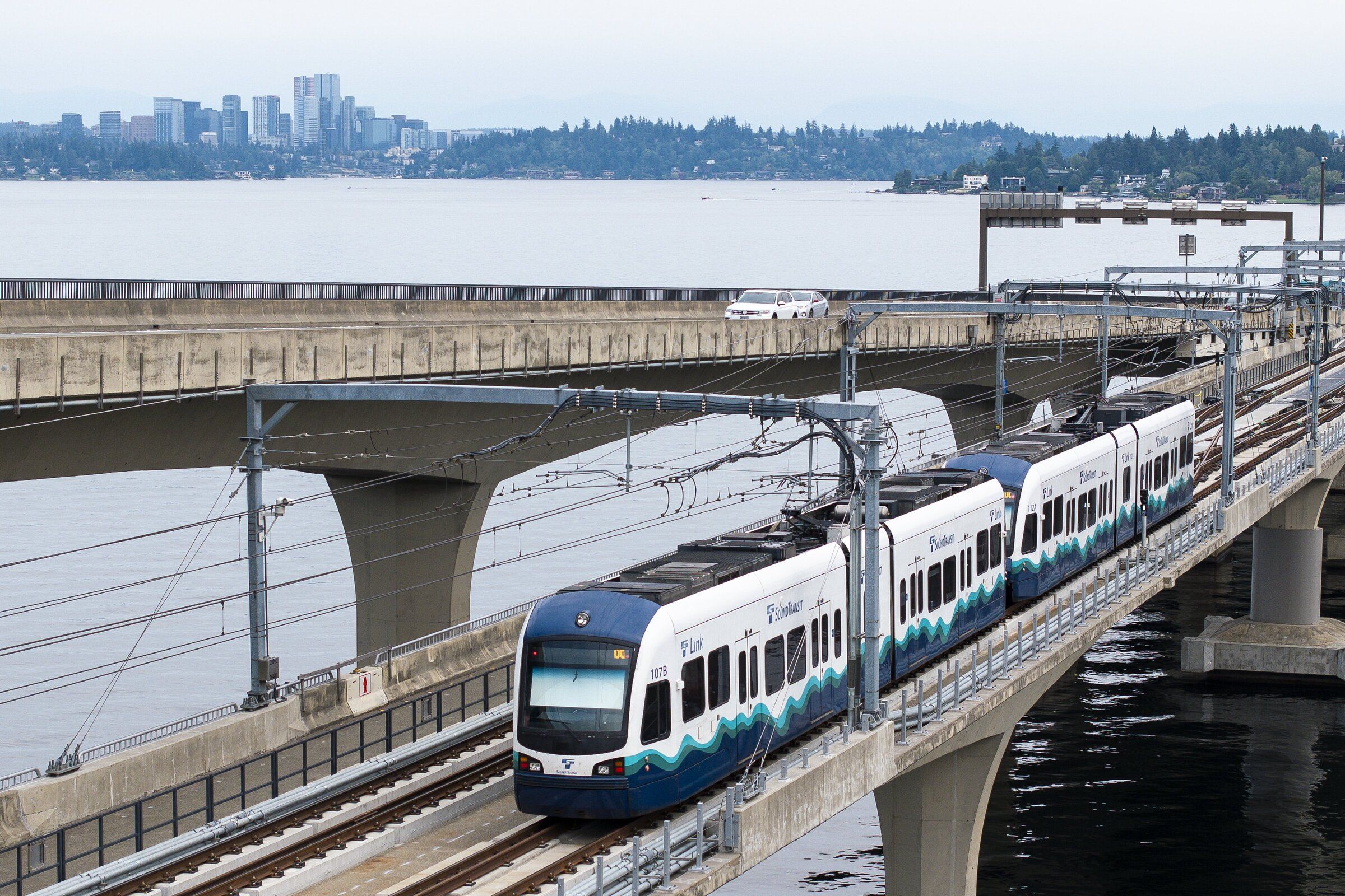 A light rail train heading to the Eastside descends at near-freeway speed toward Lake Washington’s floating pontoons, thanks to novel track supports where the I-90 bridge hinges, between land and water. (Kevin Clark / The Seattle Times)
