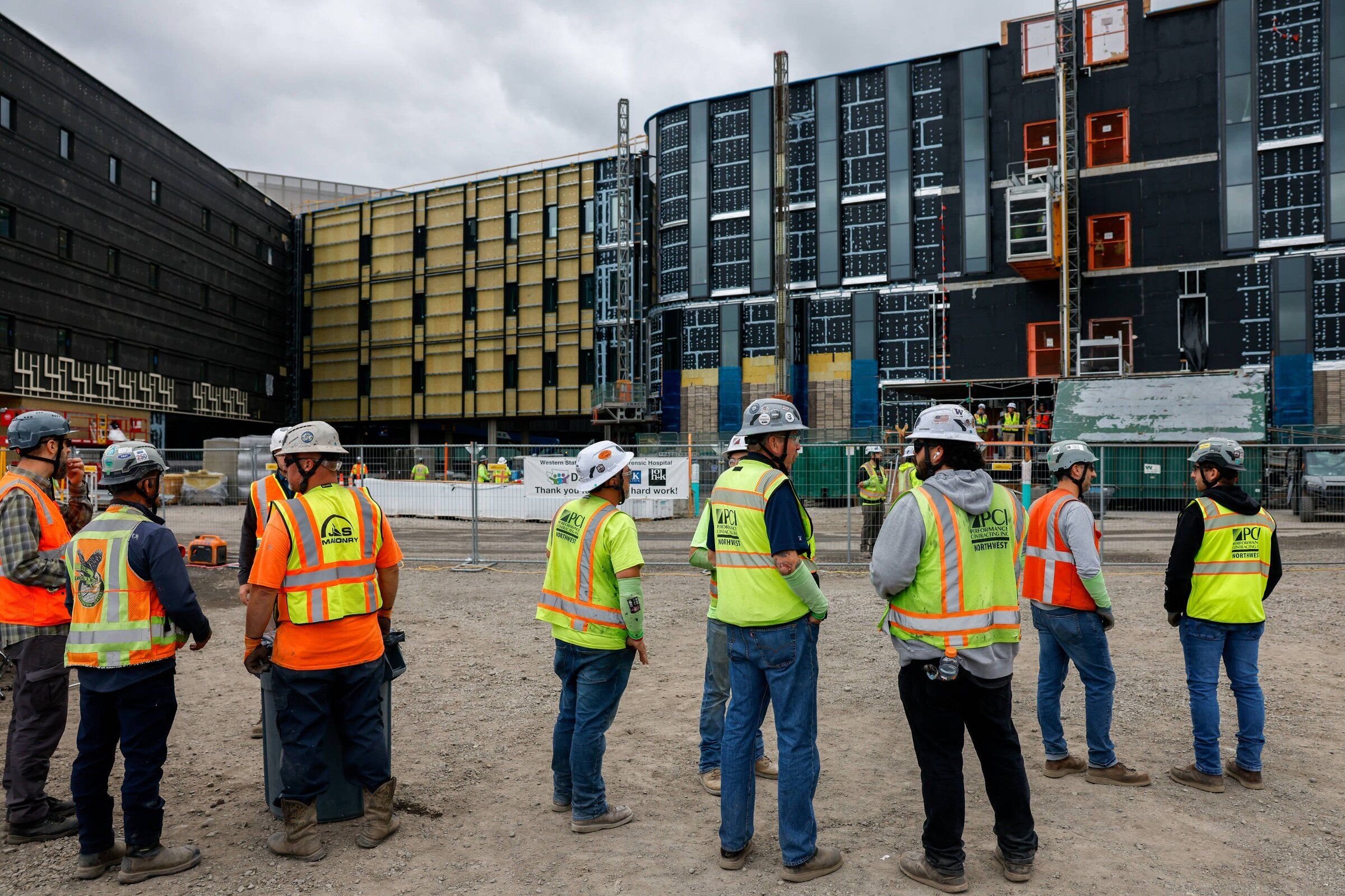 Workers stand outside the under-construction state psychiatric hospital at the Western State Hospital campus in Lakewood, Pierce County, on Friday. (Andrew Burke-Stevenson / The Seattle Times)