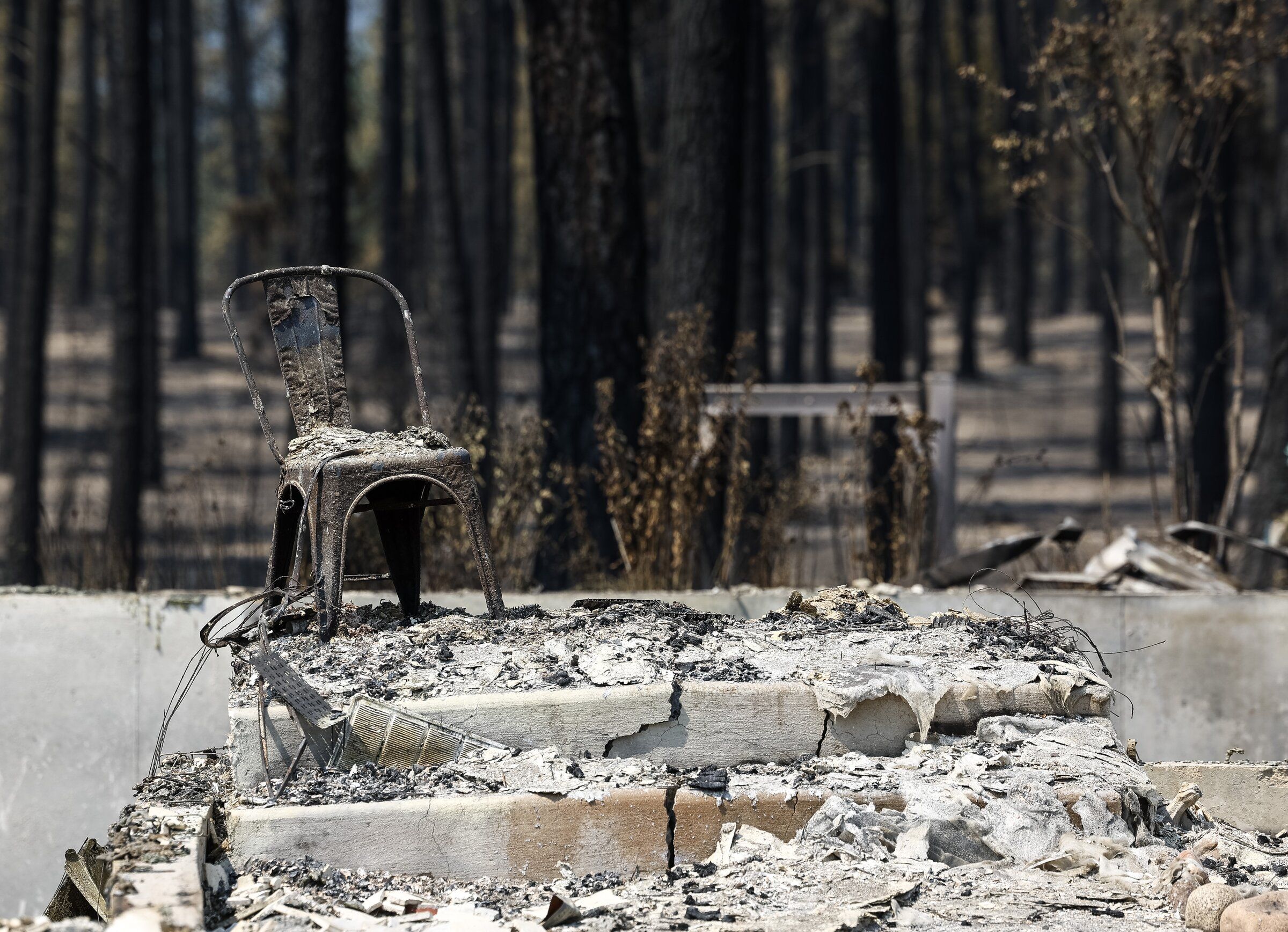 A charred chair sits on the front stoop of a home destroyed by the Old Trails fire on Aug. 5 in Spokane. (Nick Wagner / The Seattle Times)