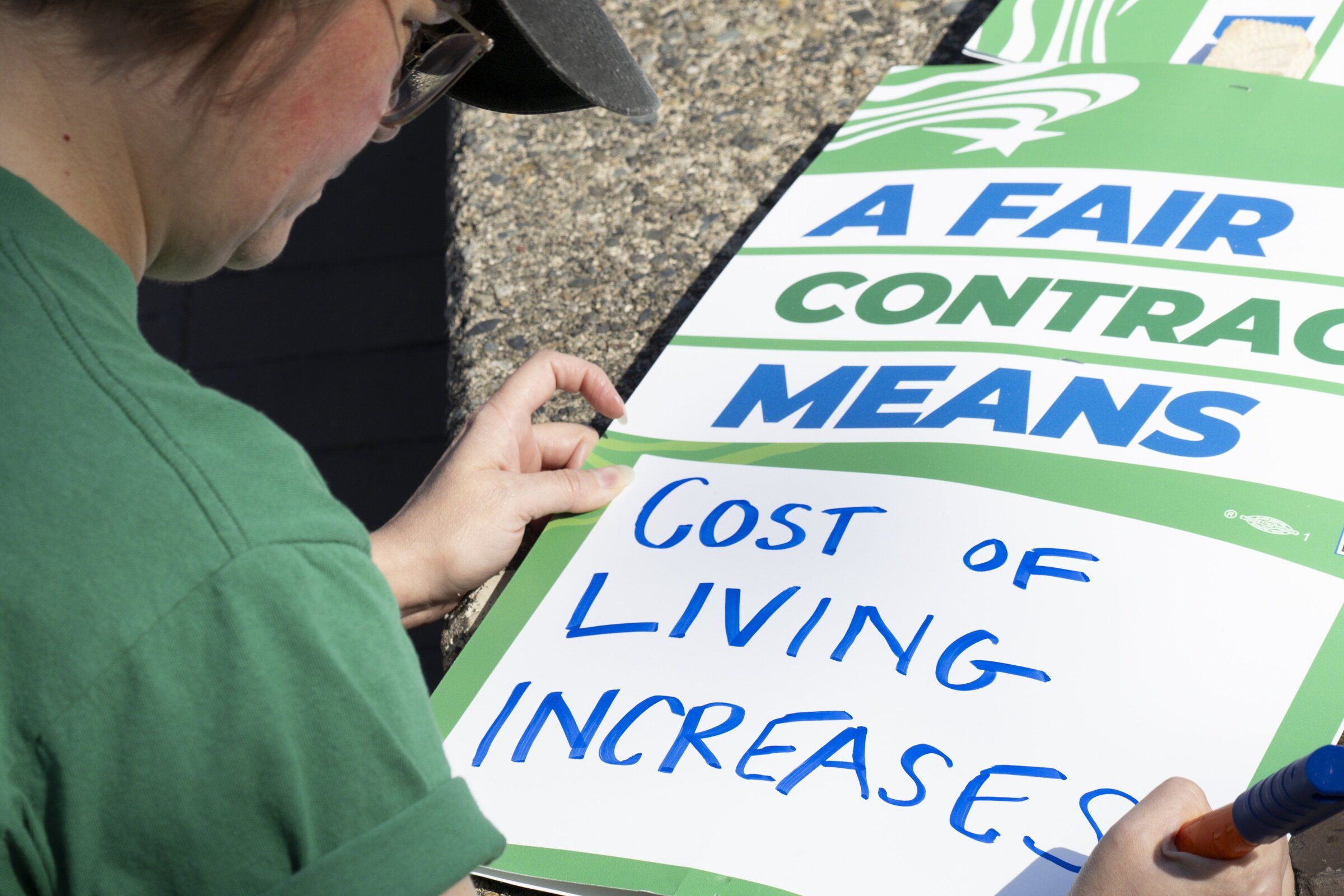 Alex Hines prints on a union-supporting sign Monday morning on Red Square at the University of Washington. (Kevin Clark / The Seattle Times)