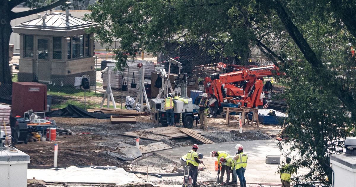 Crews remove the granite seal on the White House helipad, signaling potential project delays