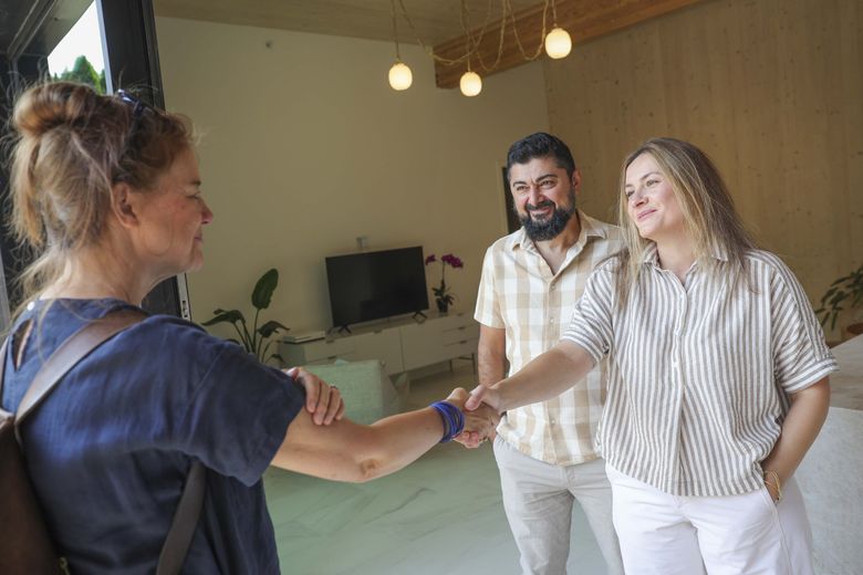 Architect Susan Jones, left, meets with homeowners Abdurrahman Hussain, 49, and Susan Farzaliyeva, 40, inside the Kenmore house that was built with mass timber.  The couple sought out Jones’ expertise when designing their home. (Ivy Ceballo / The Seattle Times)