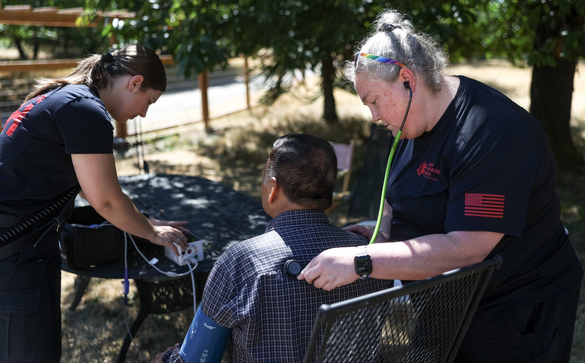 Bharat Mankad receives medical care from Vashon Island’s mobile medical team, a program unique in Washington state that offers free urgent care at home. Nurse practitioner Katie Burke (right) and registered nurse Ashley Soares (left) arrived after Mankad’s son scheduled an appointment because his wheezing had worsened. (Nick Wagner / The Seattle Times)