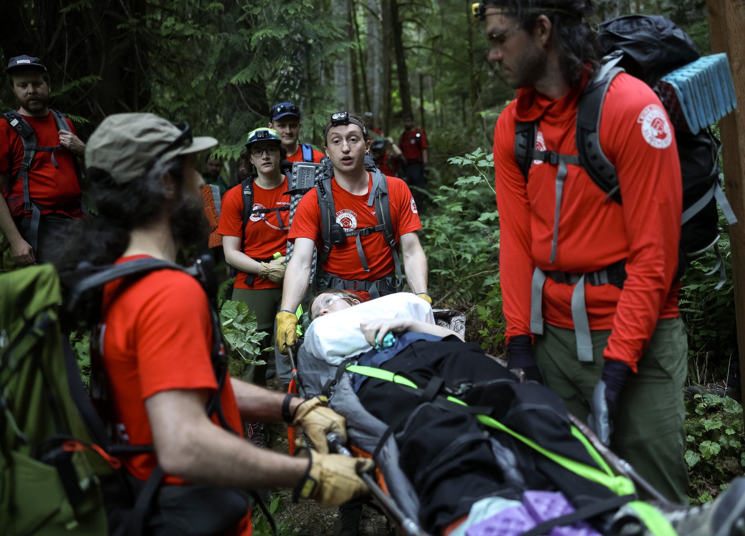 Beni Snow, a team leader in training with King County Explorer Search & Rescue, communicates with team members as they transport Kaelynn Condron during a training exercise in July near North Bend. (Nick Wagner / The Seattle Times)