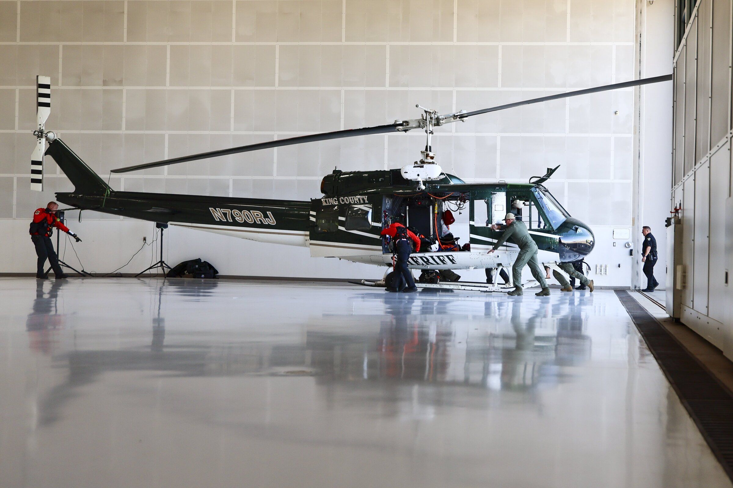 Members of the King County Sheriff’s Office air support unit place a rescue helicopter in a hangar before a news conference at King County International Airport in Seattle in July. (Kevin Clark / The Seattle Times)