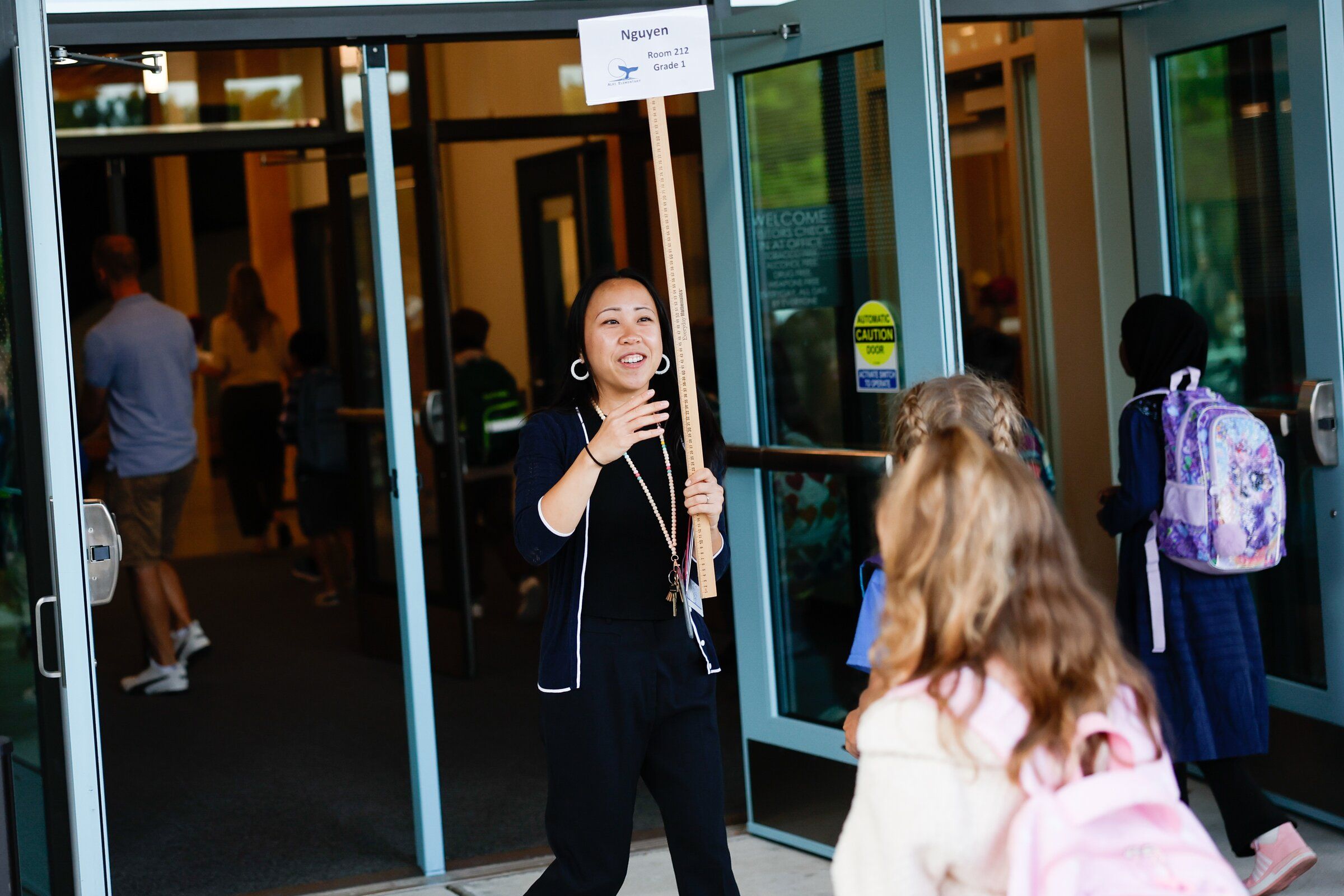 Teacher Rebecca Nguyen waves her class into the building on the first day of school at Alki Elementary in Seattle on Sept. 2. (Karen Ducey / The Seattle Times)