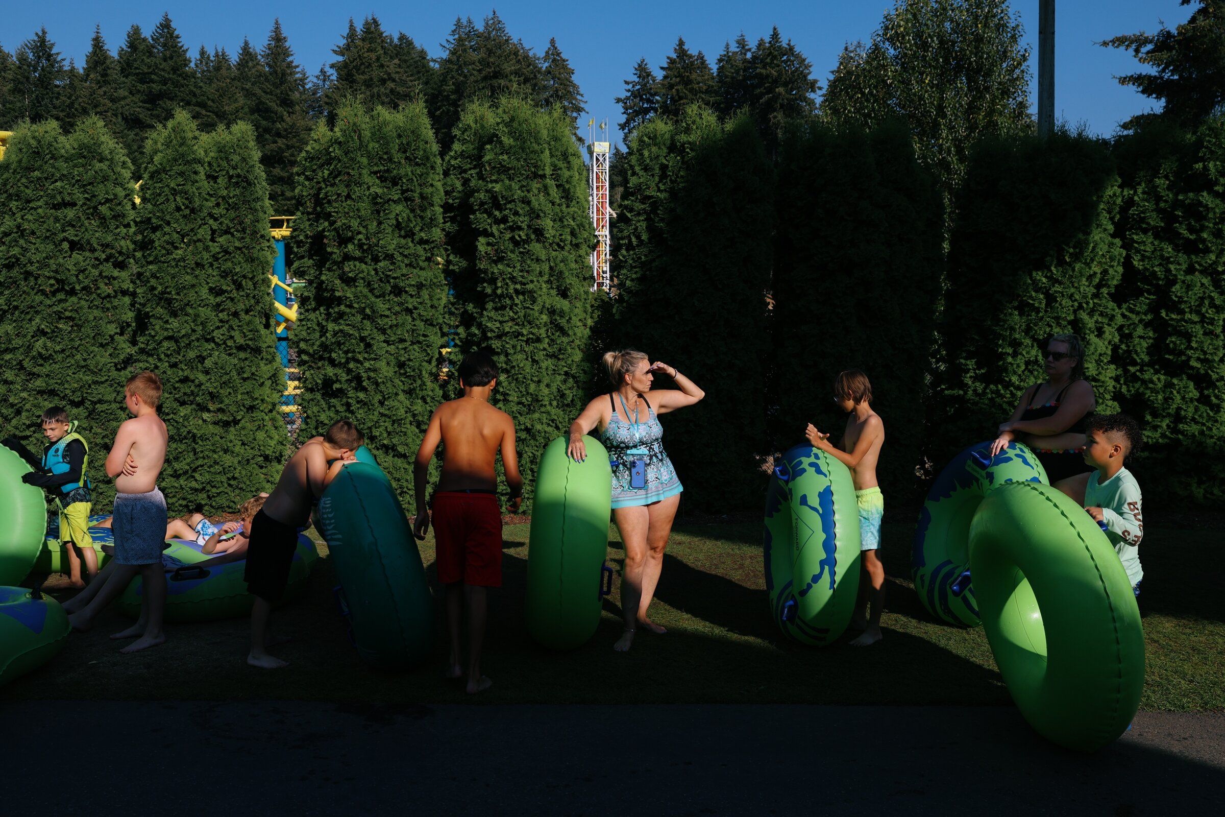Waiting their turn for a water slide, visitors stand with inner tubes in the late-afternoon sun. (Genna Martin / special to The Seattle Times)