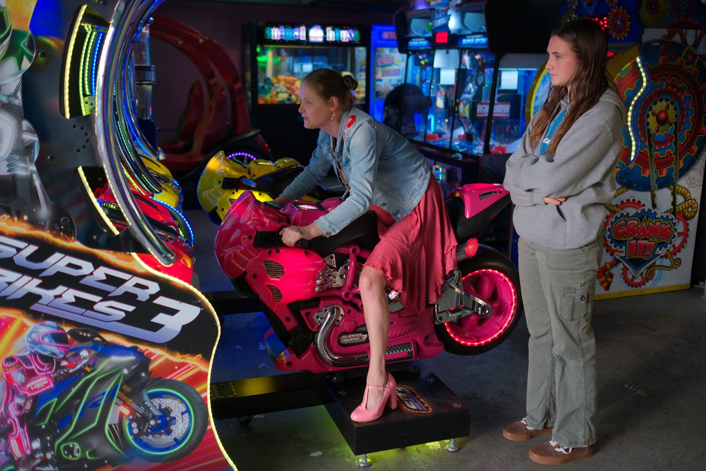Sequim’s Sierra Brittell plays an arcade motorcycle game while her daughter, Abby Brown, watches at Wild Waves on Aug. 29. Both were saddened by the closure of the park they had visited for many years. “It’s such a Pacific Northwest park — with these trees and Timberhawk,” Brown said. (Genna Martin / special to The Seattle Times)
