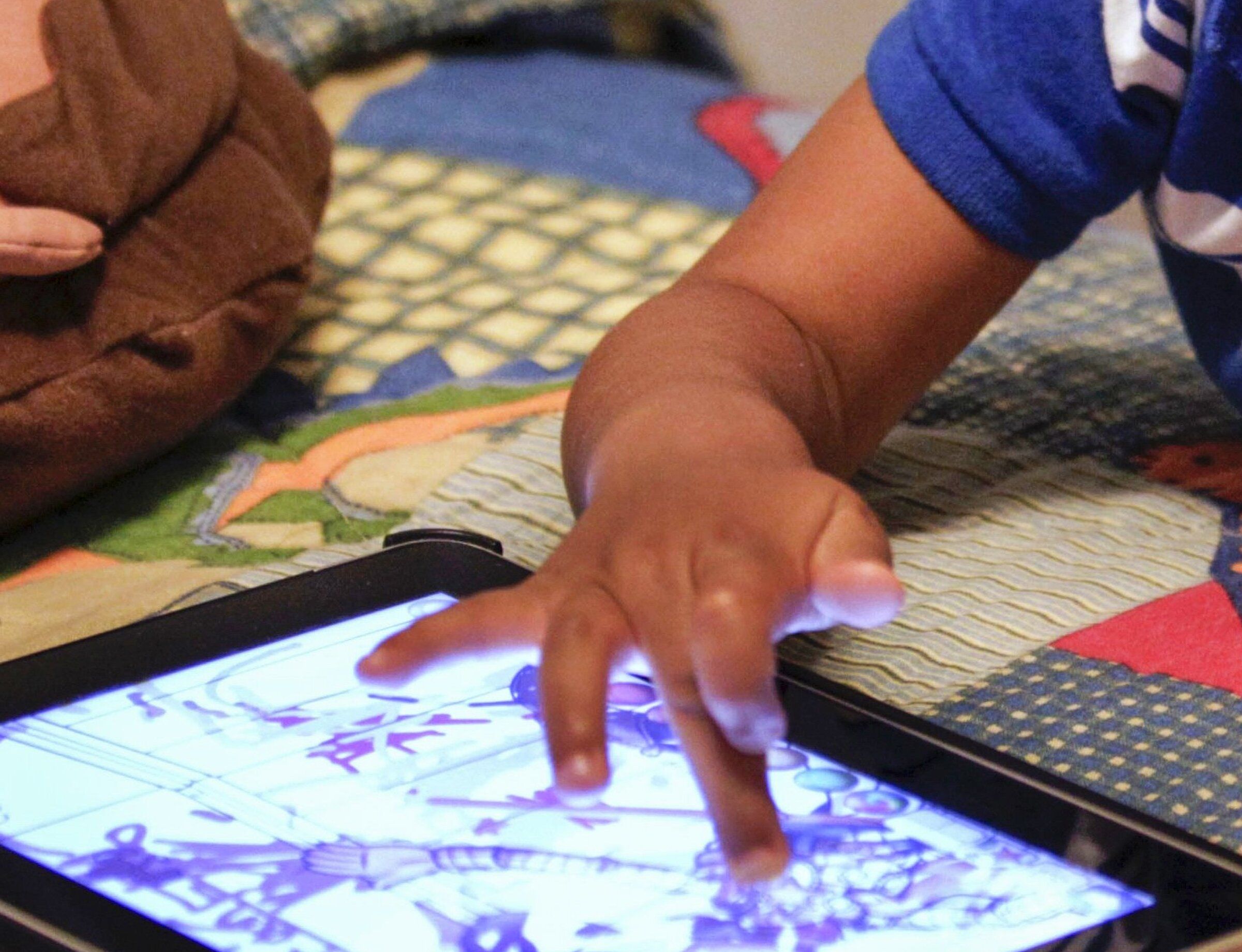 In this Oct. 21, 2011, photo, a child plays with an iPad in his bedroom. Seattle Public Schools announced Monday that the district’s youngest learners will no longer have individual access to iPads beginning in January 2027, in an effort to reduce screen time during school hours. (Gerald Herbert / The Associated Press, file)