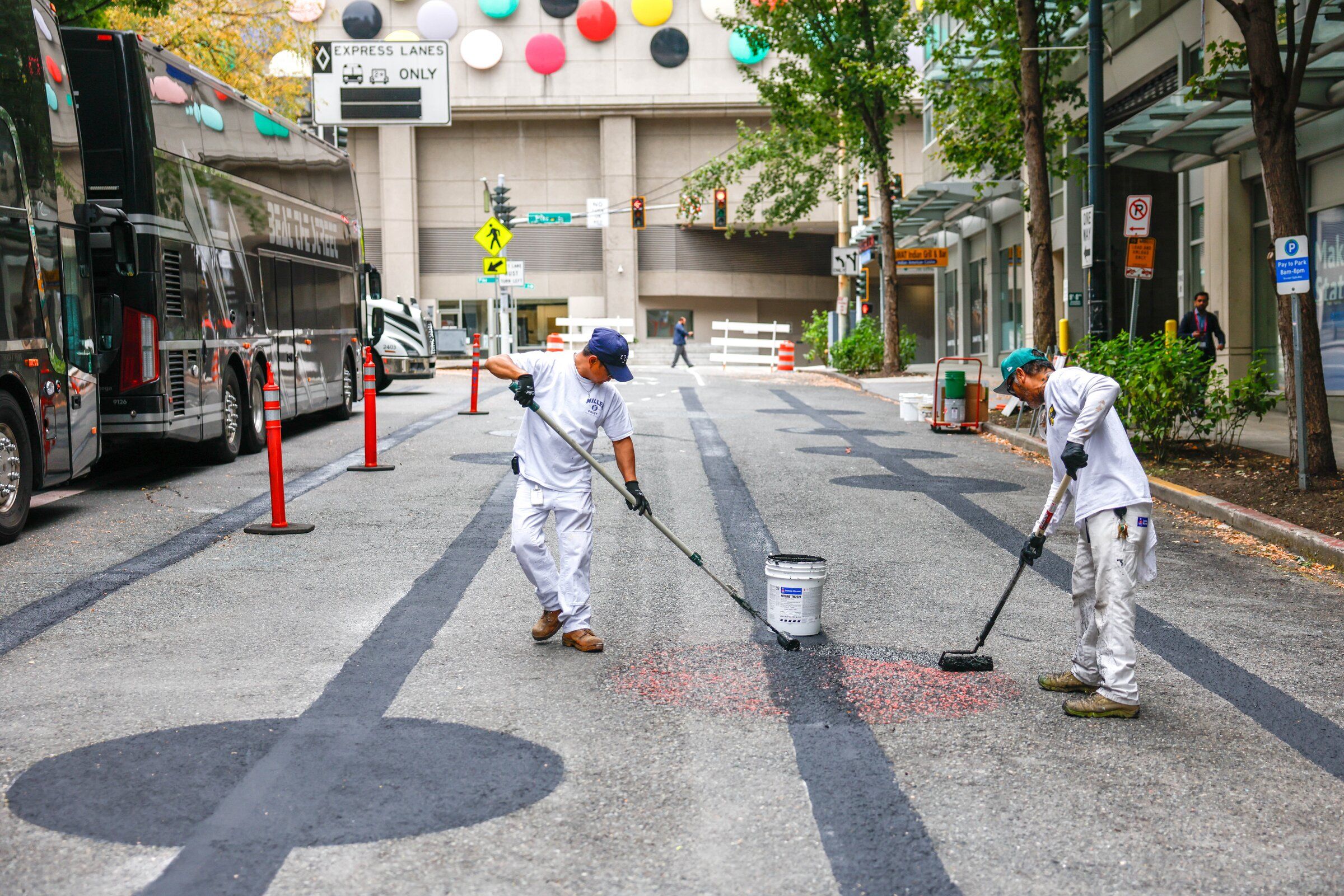 Voltaire Valdez and Von Phasavath paint over a street mural on Ninth Avenue between Pine and Pike near the Seattle Convention Center on Wednesday, Sept. 23.  (Andrew Burke-Stevenson / The Seattle Times)