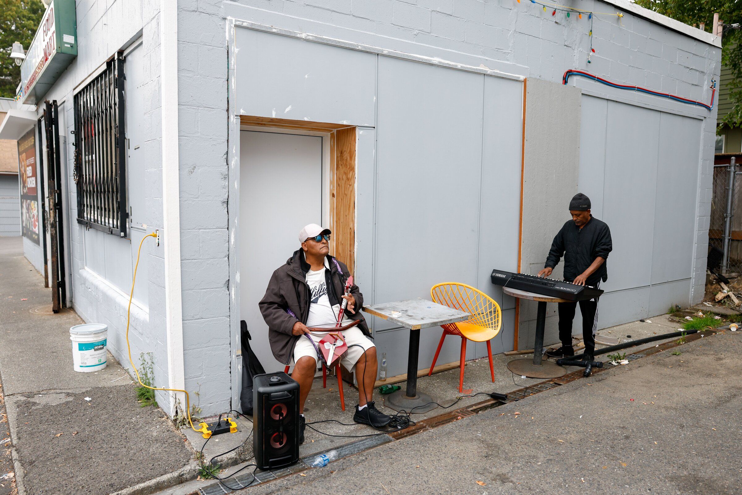 Daniel Zeina and Alemayehu Gulelat play music outside Quick Pack Food Mart in Seattle’s Central District on Thursday. While the instruments change day to day, here Zeina is playing a masinko, a traditional Ethiopian single-stringed instrument. (Andrew Burke-Stevenson / The Seattle Times)