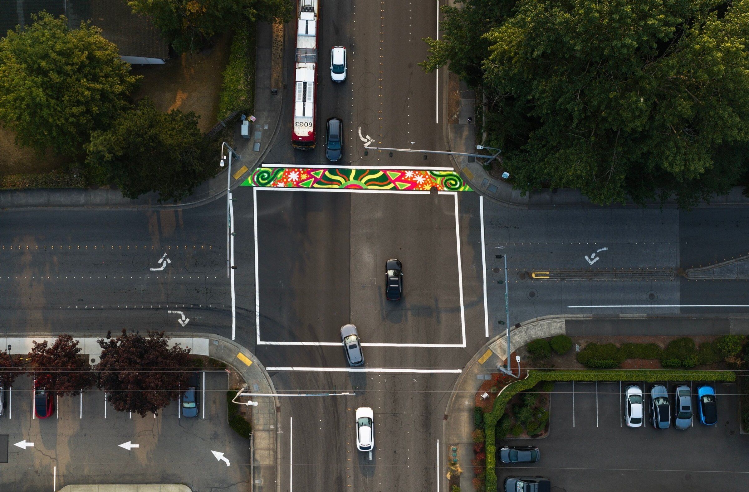 Vehicles approach a new asphalt art installation in Bellevue designed by Seattle artist Nikita Ares. Bellevue is testing colorful crosswalks to see if they can improve pedestrian safety and minimize collisions. (Chance Merchant)