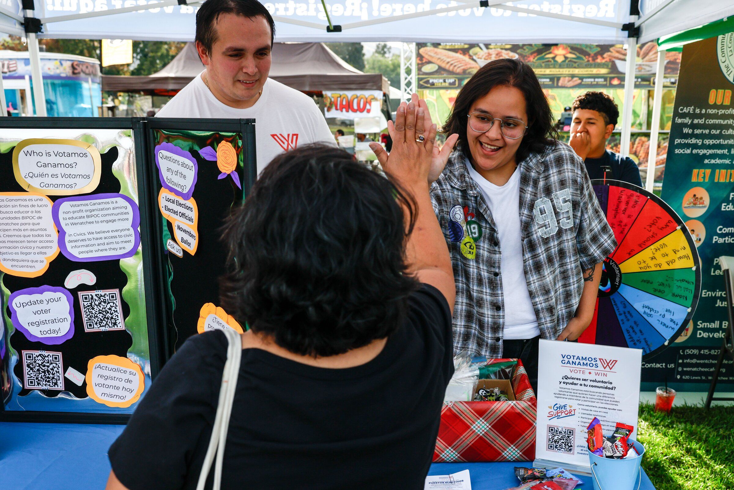 Mars Hinojos, a community activist with the nonprofit Vote Win/Votamos Ganamos, high-fives Stacey Willoughby, who stopped by the group’s tent during last year’s Fiestas Mexicanas celebrating Mexican Independence Day. (Andrew Burke-Stevenson / The Seattle Times)