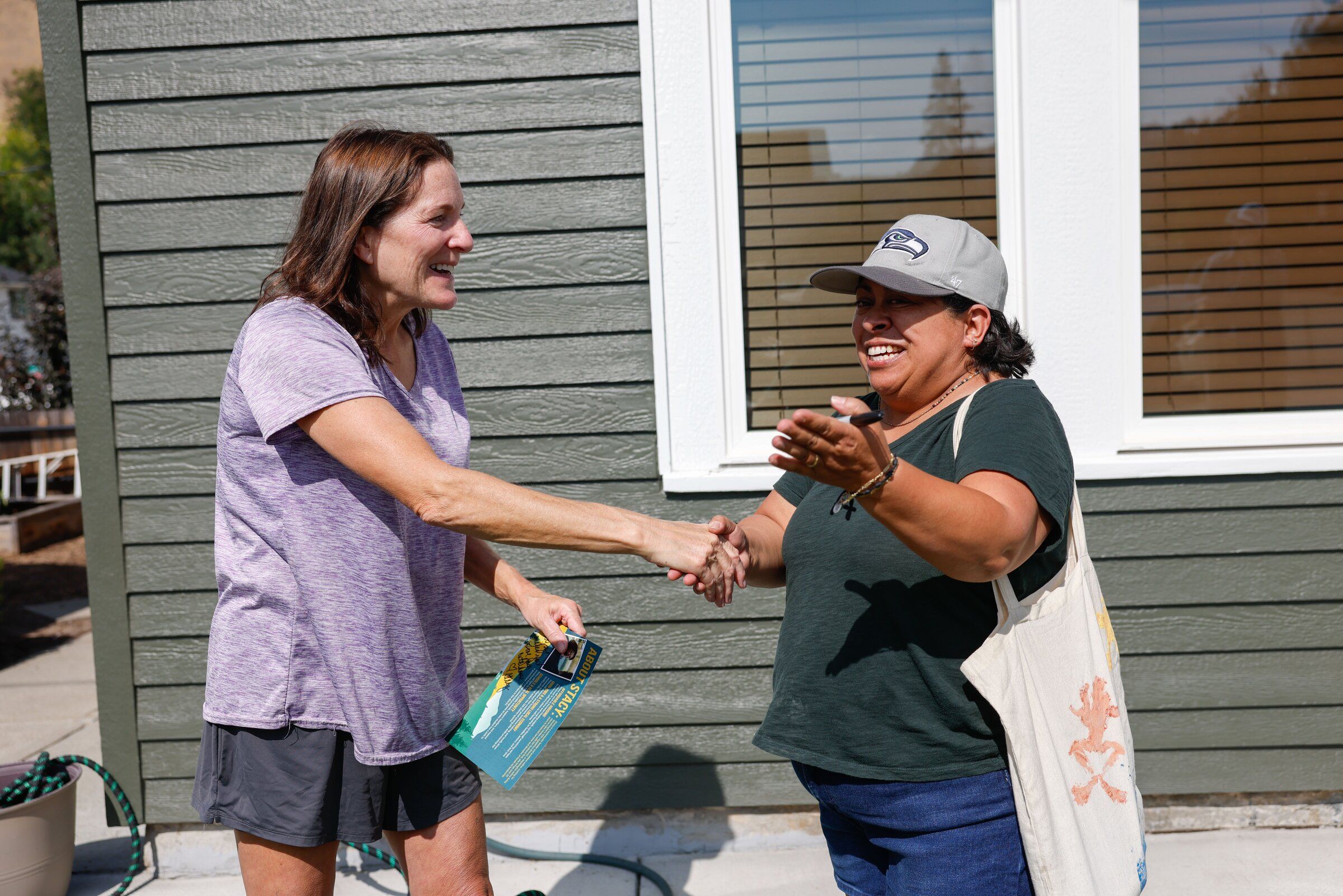 Jennifer Finley, left, and state House candidate Stacey Willoughby shake hands outside Finley’s home in Cashmere. (Andrew Burke-Stevenson / The Seattle Times)